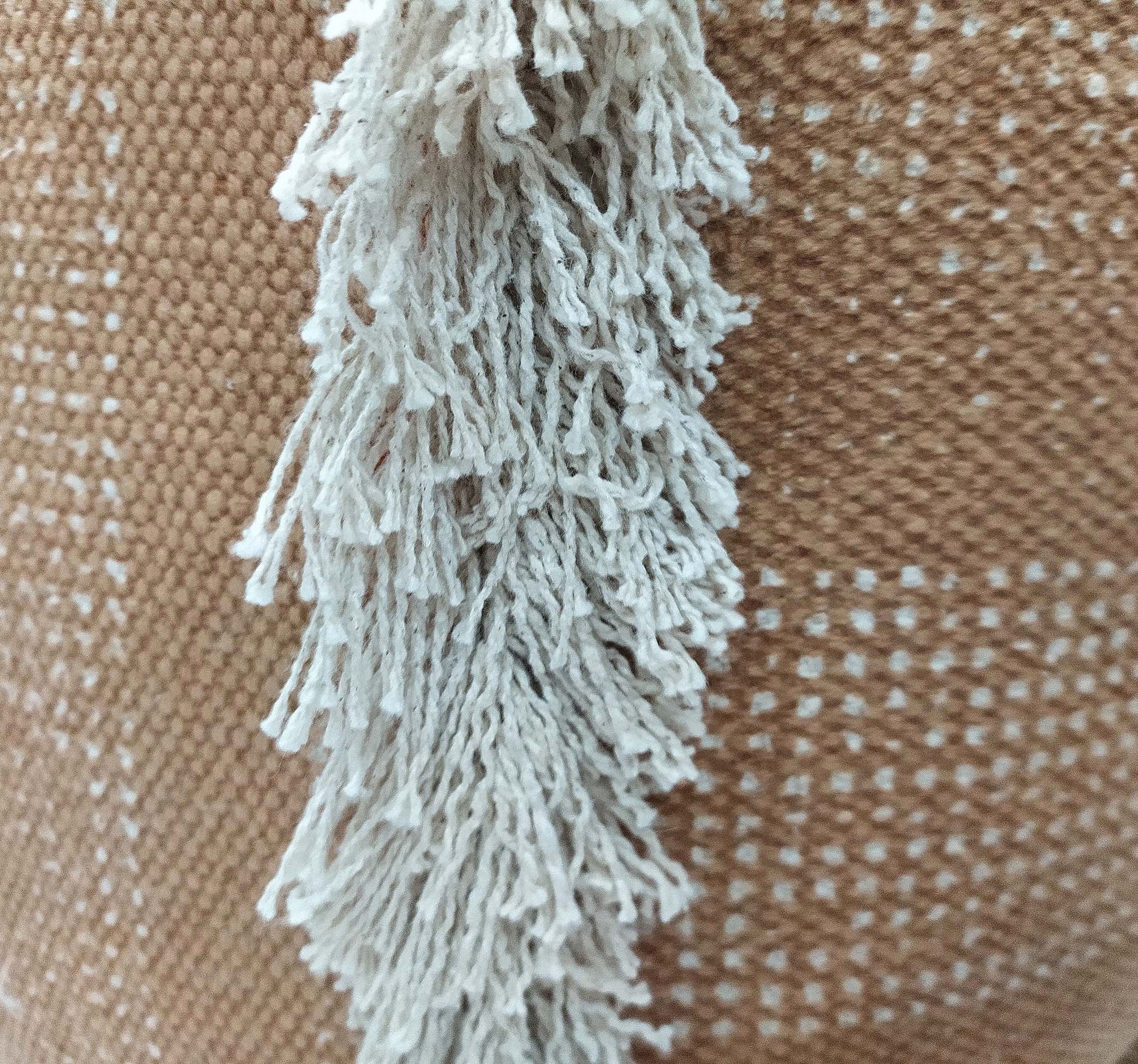 Close-up of the beige woven fabric with a white fringe running vertically, used for the RAMSHA HOME Pouf With Leather Handle PF-049. It has a subtle checkered pattern, adding texture and style to this cotton pouf.