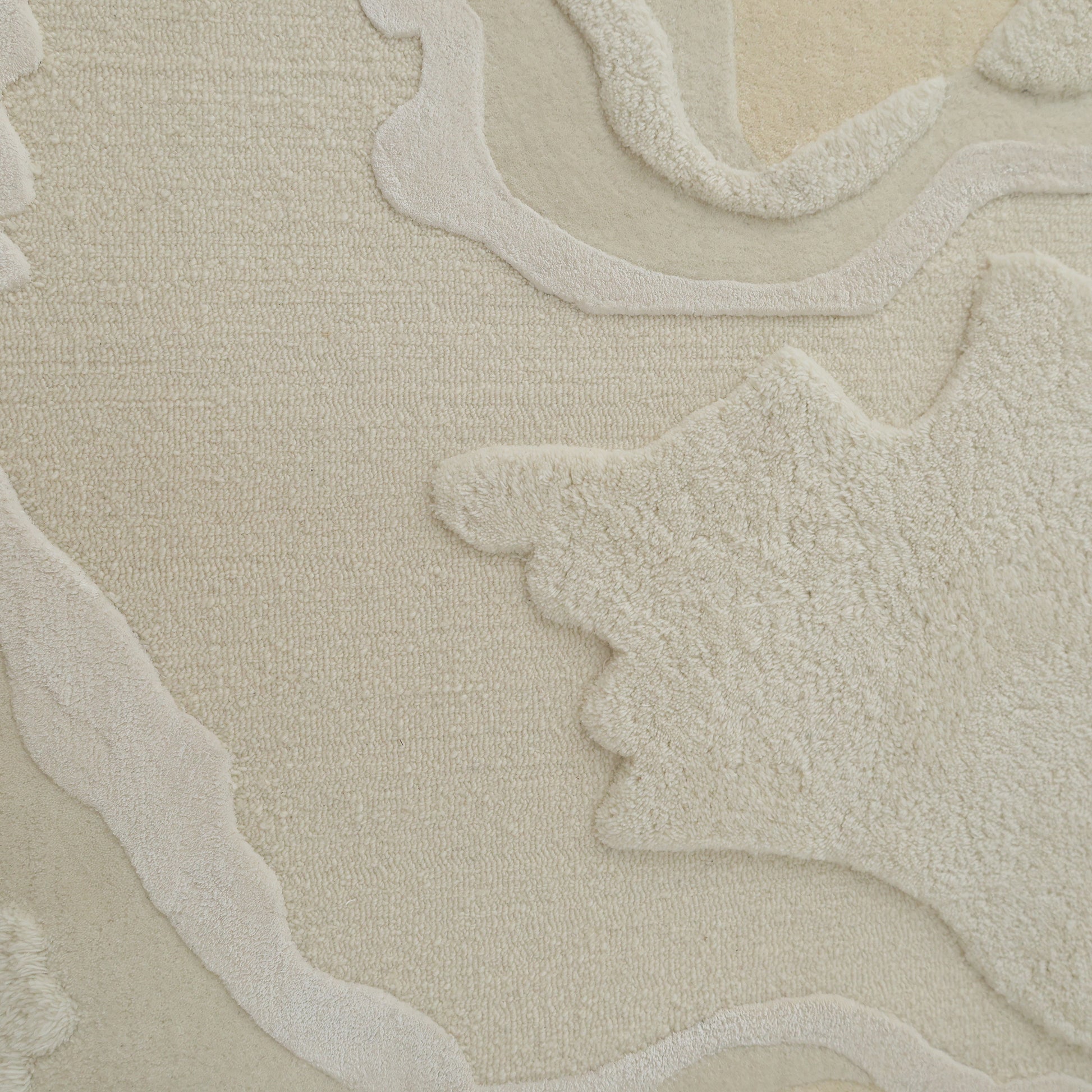 A close-up of the RAMSHA HOME Handcrafted Natural White Area Rug – HTWV-129 highlights its textured, modern abstract design in beige and off-white with raised, irregular shapes and soft, wavy contours for a layered look.