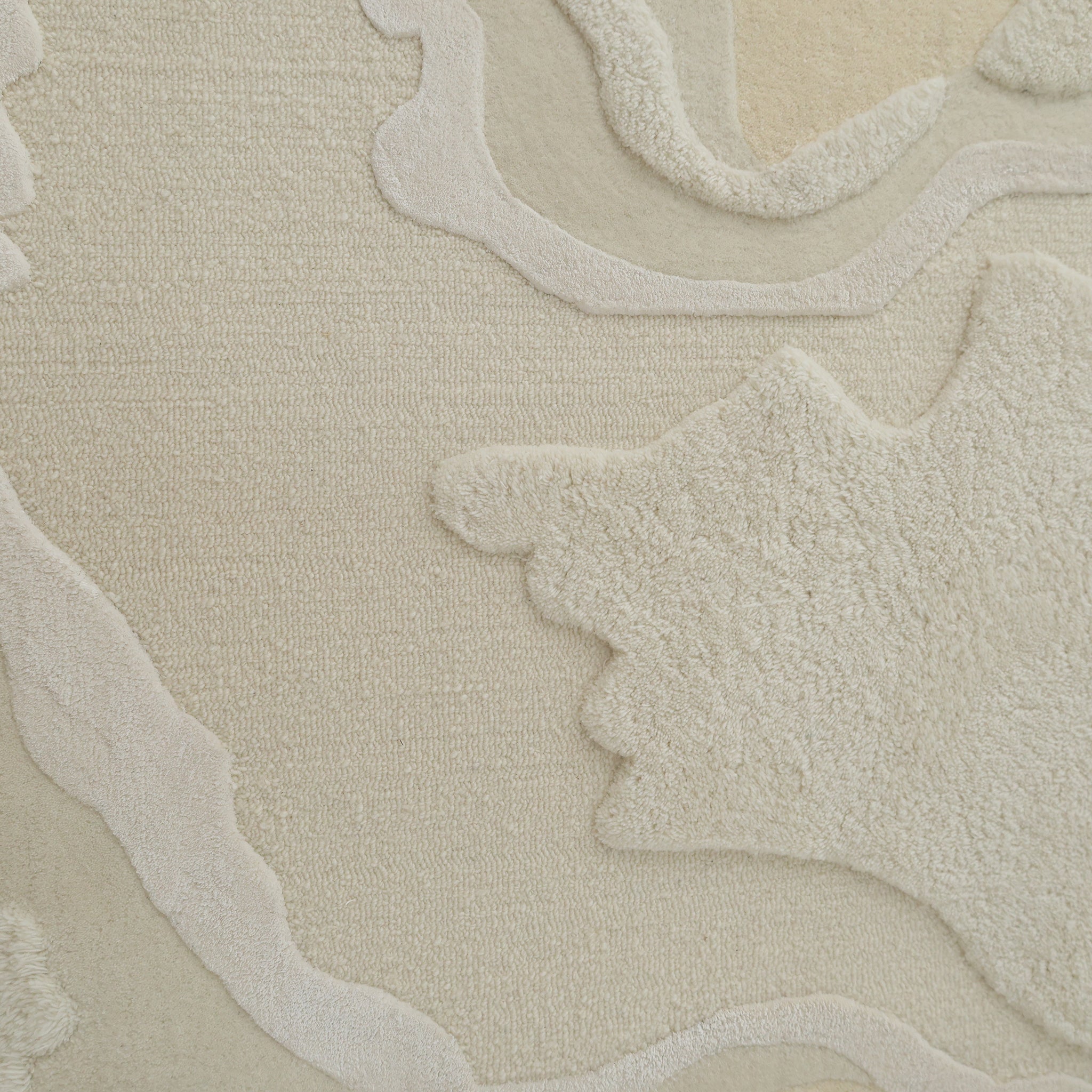A close-up of the RAMSHA HOME Handcrafted Natural White Area Rug – HTWV-129 highlights its textured, modern abstract design in beige and off-white with raised, irregular shapes and soft, wavy contours for a layered look.