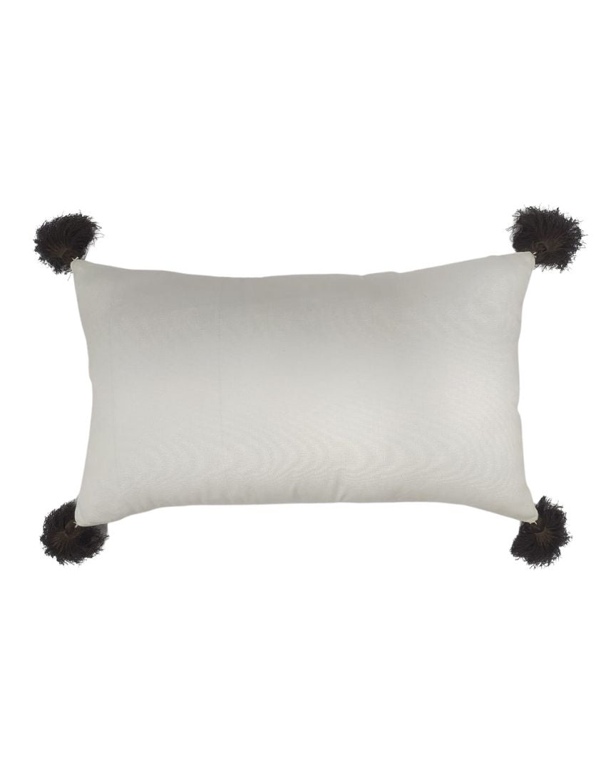 The RAMSHA HOME White & Brown Cushion CS-138 features a rectangular white polyester design with four black tassels, one at each corner, adding stylish comfort and durability to any room. Shown on a plain white background.