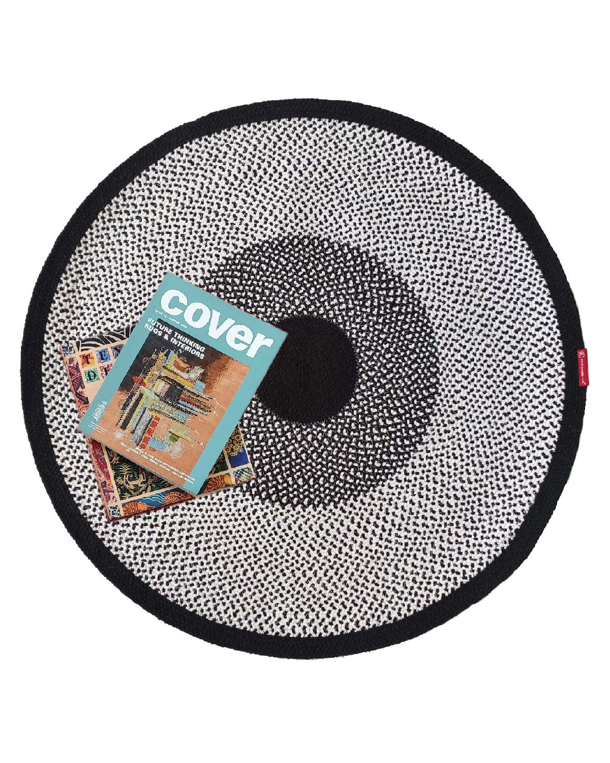 The RAMSHA HOME Black & White Color Round Braided Rug - BR 010, shown with a magazine cover and postcards on it against a white background, is a stylish cotton rug that adds charm to any space.