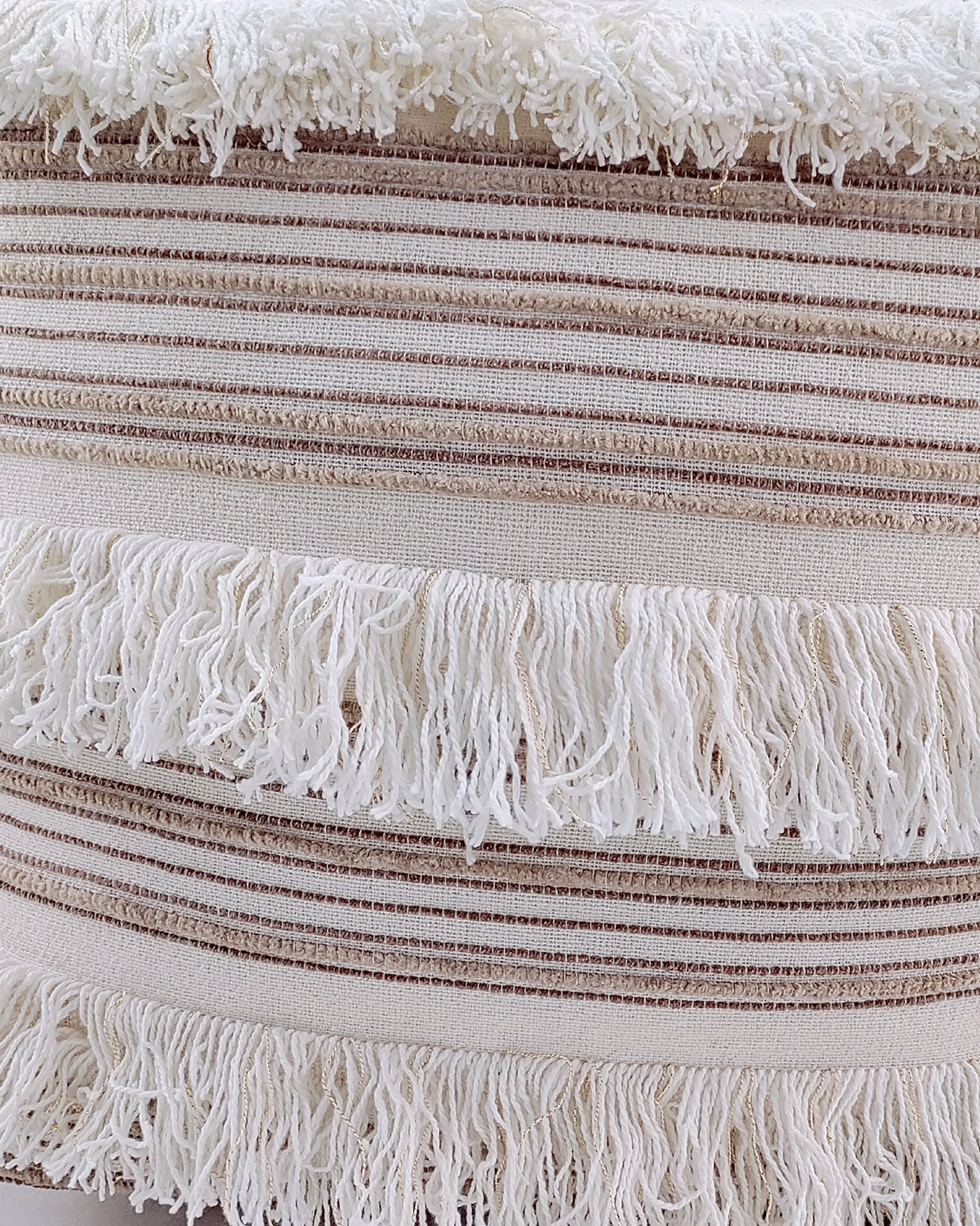Close-up of the RAMSHA HOME Cotton Boho Pouf With Fringes PF-067, showcasing its soft, textured fabric with horizontal brown and cream stripes and off-white fringed tassels—perfect for adding a cozy touch to any room.