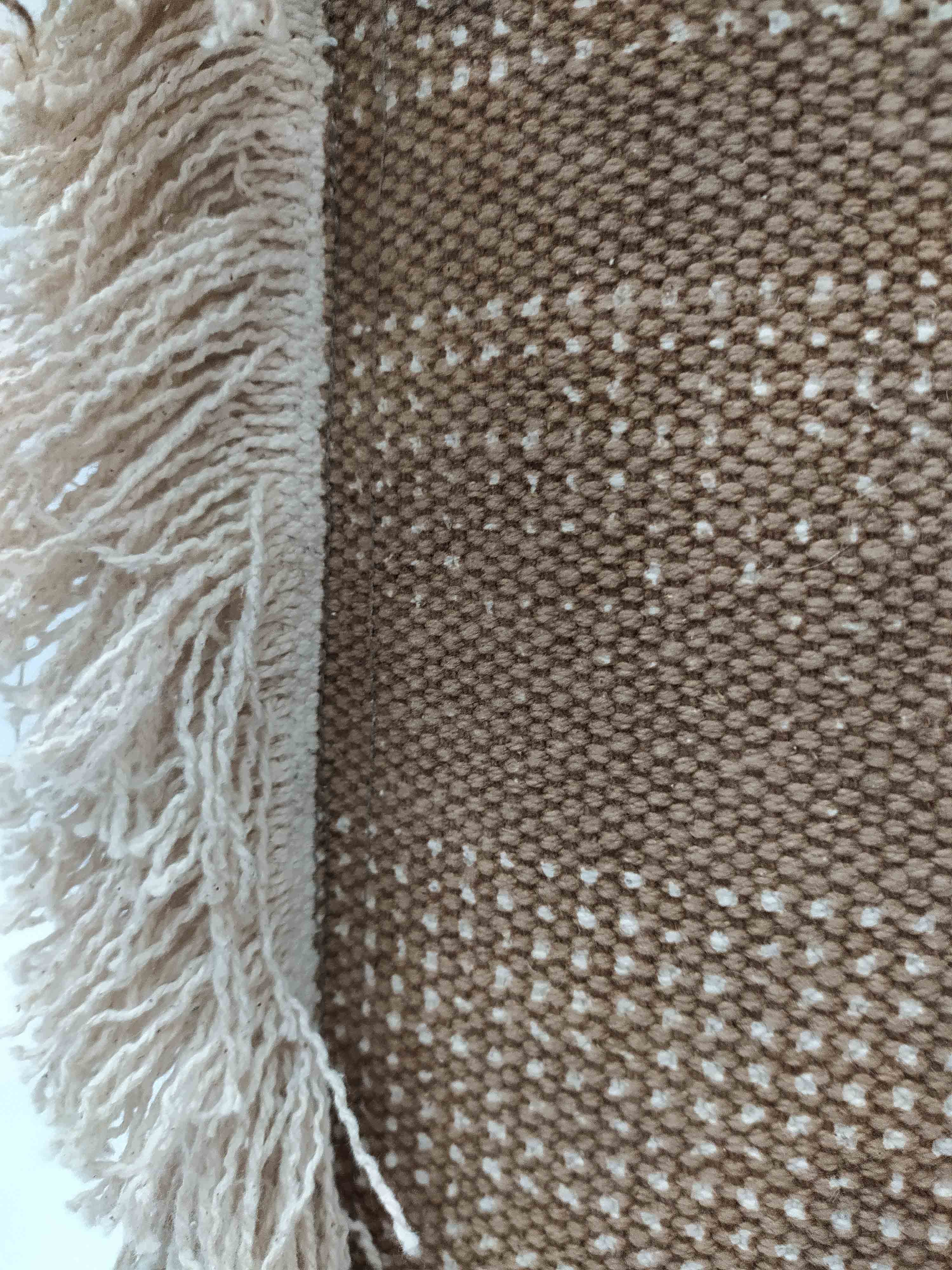 Close-up of a woven fabric with brown and beige checks and cream fringe—pairs perfectly with the RAMSHA HOME Pouf With Leather Handle PF-049 for cozy, stylish decor.