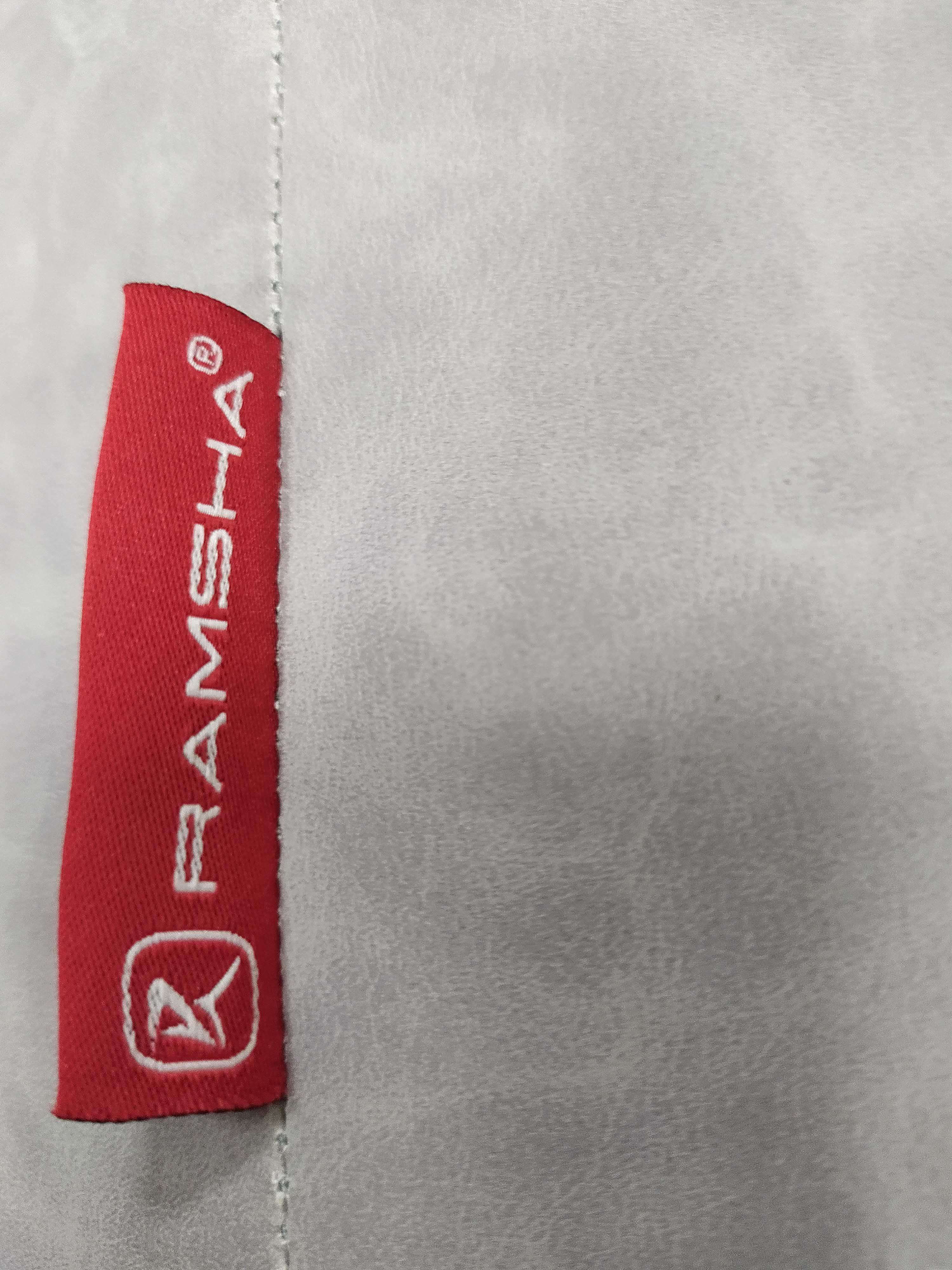 A close-up of a red fabric label with "RAMSHA HOME" and a white logo, stitched onto light gray fabric—ideal for adding style to your Leather Cylinderical Pouf or enhancing the look of cozy seating.