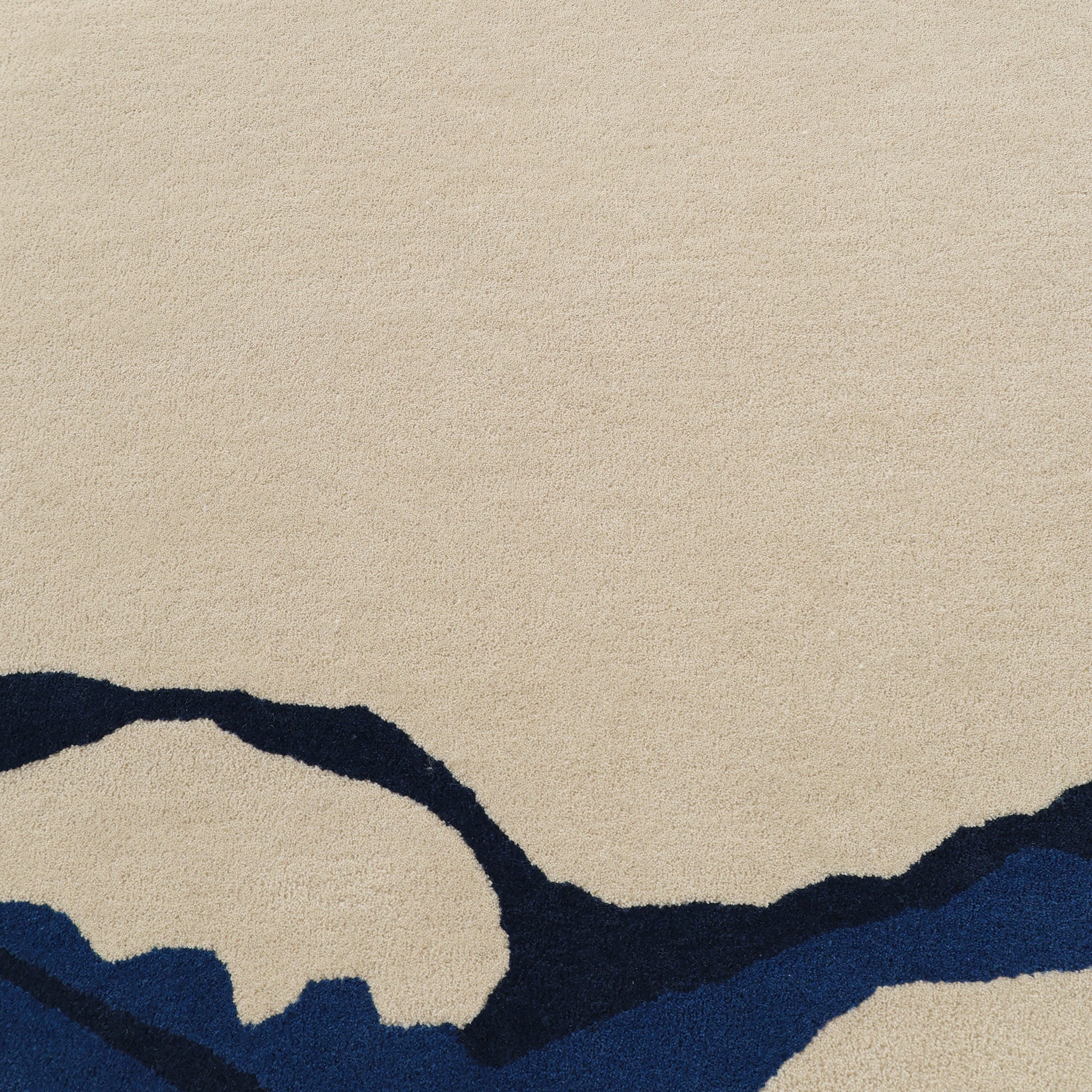 The RAMSHA HOME Round Handmade Hand Tufted Carpet HTW-64 features a beige base with an abstract pattern of dark blue and navy blue lines and shapes along the bottom edge.