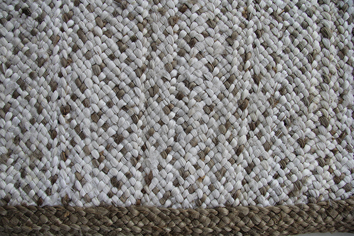 Close-up of the RAMSHA HOME Handmade Natural & White Bedroom Crochet Rug (CR 004, 200x300cm), featuring braided jute in white and beige with a thicker, darker border that emphasizes its textured look and durable natural fibers.