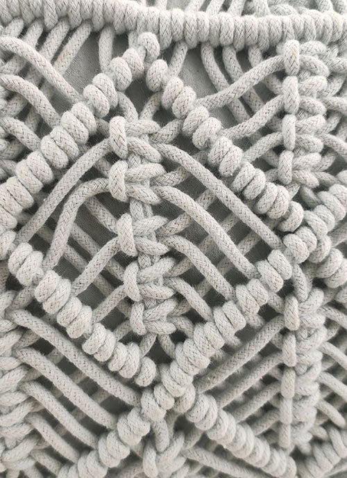 Close-up of RAMSHA HOME's Macrame Cotton Pouf shows detailed light gray boho-style patterns with knotted ropes in geometric diamonds—chic décor for any space.