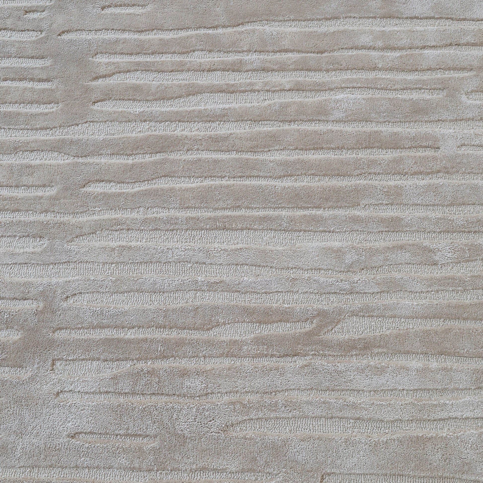 A close-up of the RAMSHA HOME Home Decor Handmade Area Rug - HTV 17 shows its soft, hand-tufted design with a neutral texture and subtle, horizontal wavy stripes.
