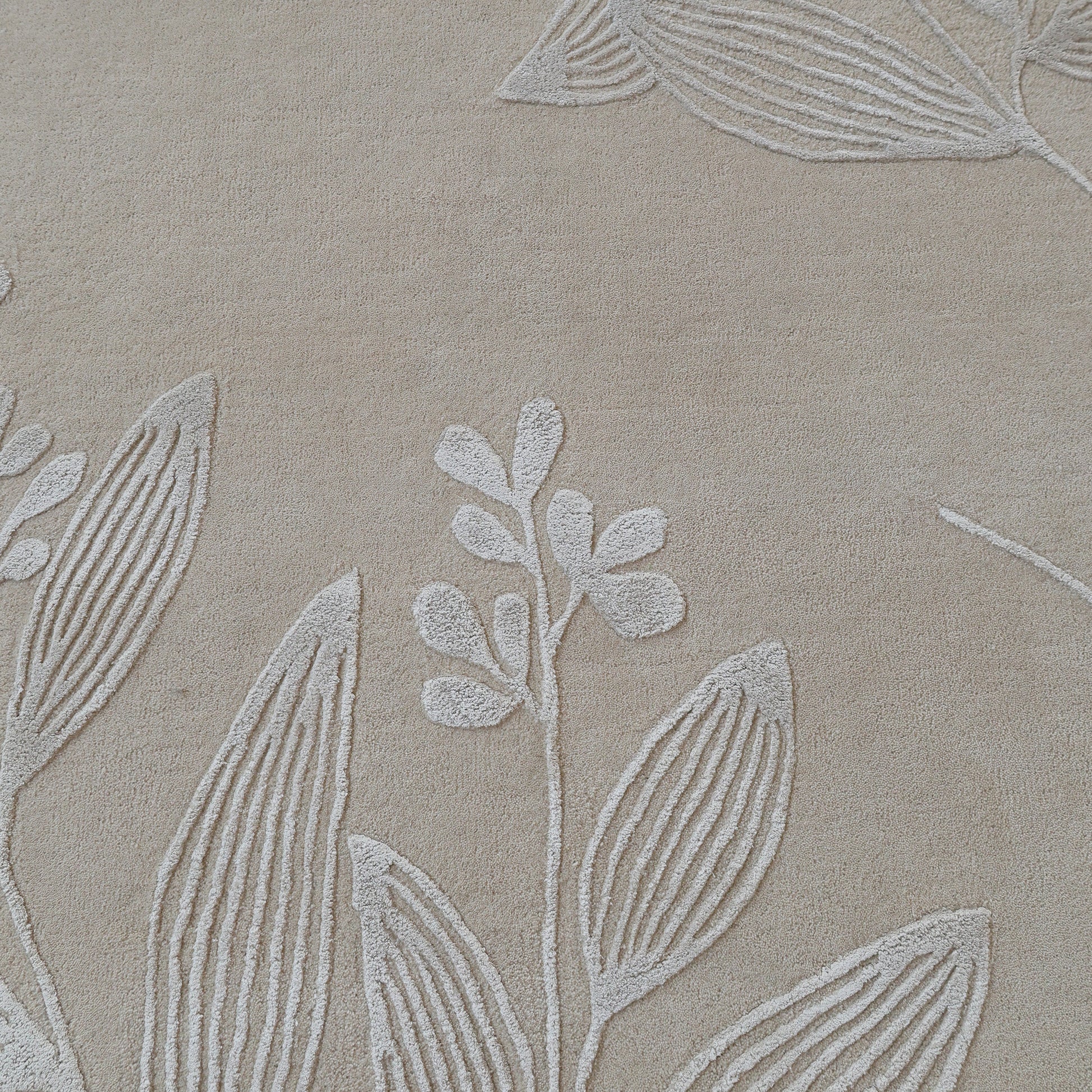 The RAMSHA HOME Natural Beige & Ivory Handmade Area Rug (HTWV-146) features a textured fabric with an embossed botanical leaf and stem pattern, creating a subtle, raised design reminiscent of hand-tufted wool rugs.