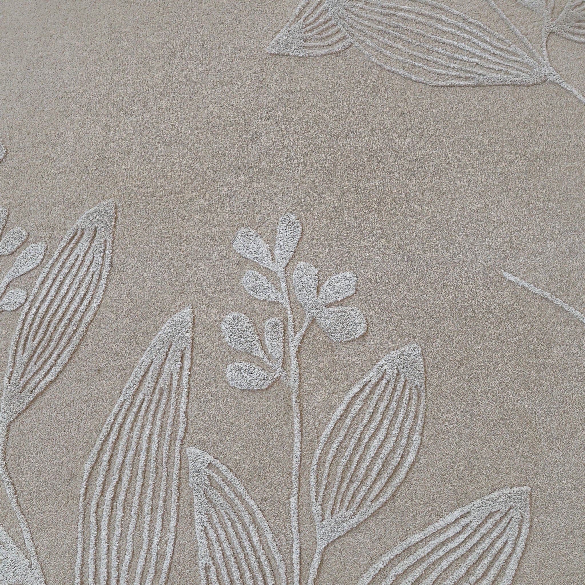 The RAMSHA HOME Natural Beige & Ivory Handmade Area Rug (HTWV-146) features a textured fabric with an embossed botanical leaf and stem pattern, creating a subtle, raised design reminiscent of hand-tufted wool rugs.