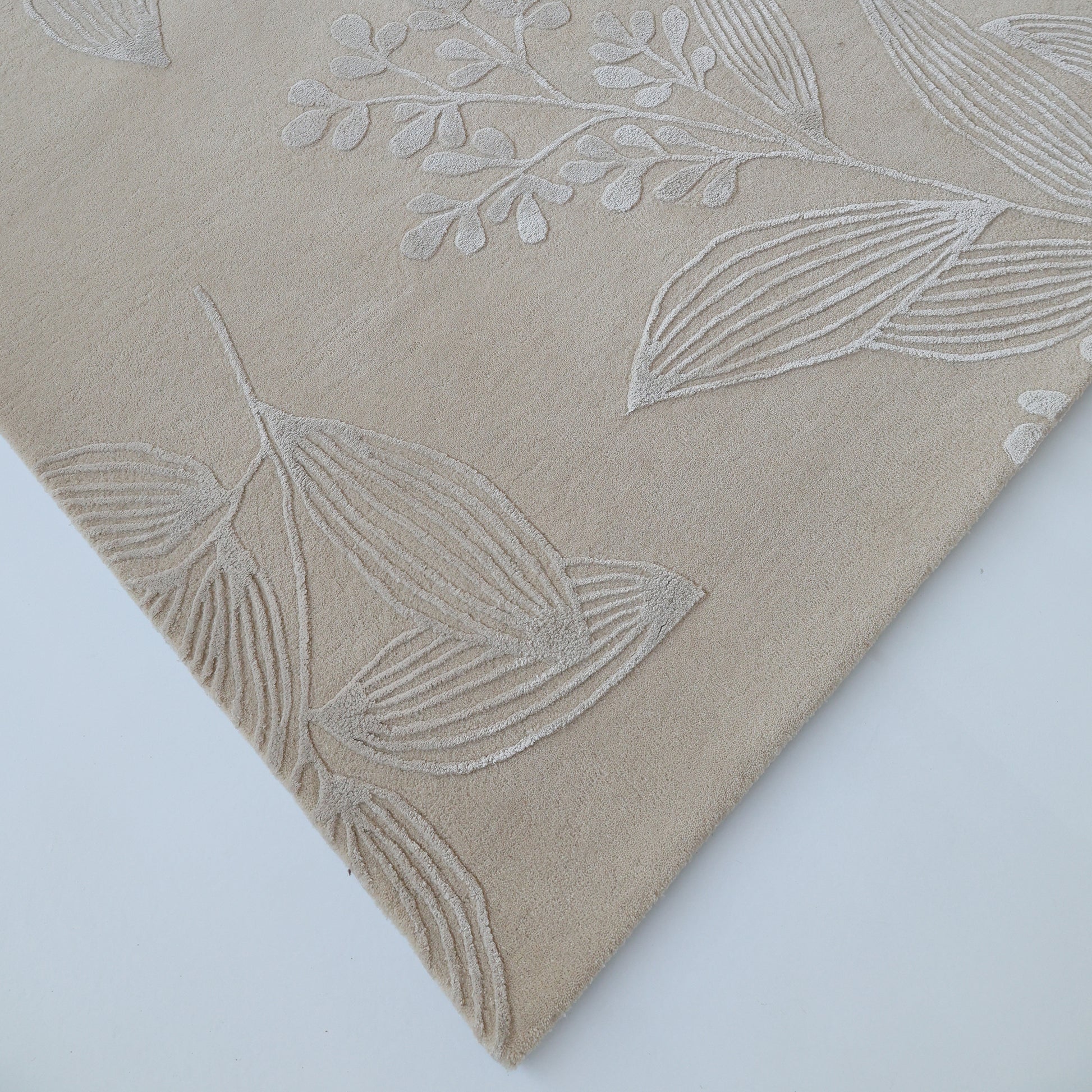 A close-up of the RAMSHA HOME Natural Beige & Ivory Handmade Area Rug (HTWV-146) shows its embossed leaf and branch pattern in ivory on beige, displayed against a white background.