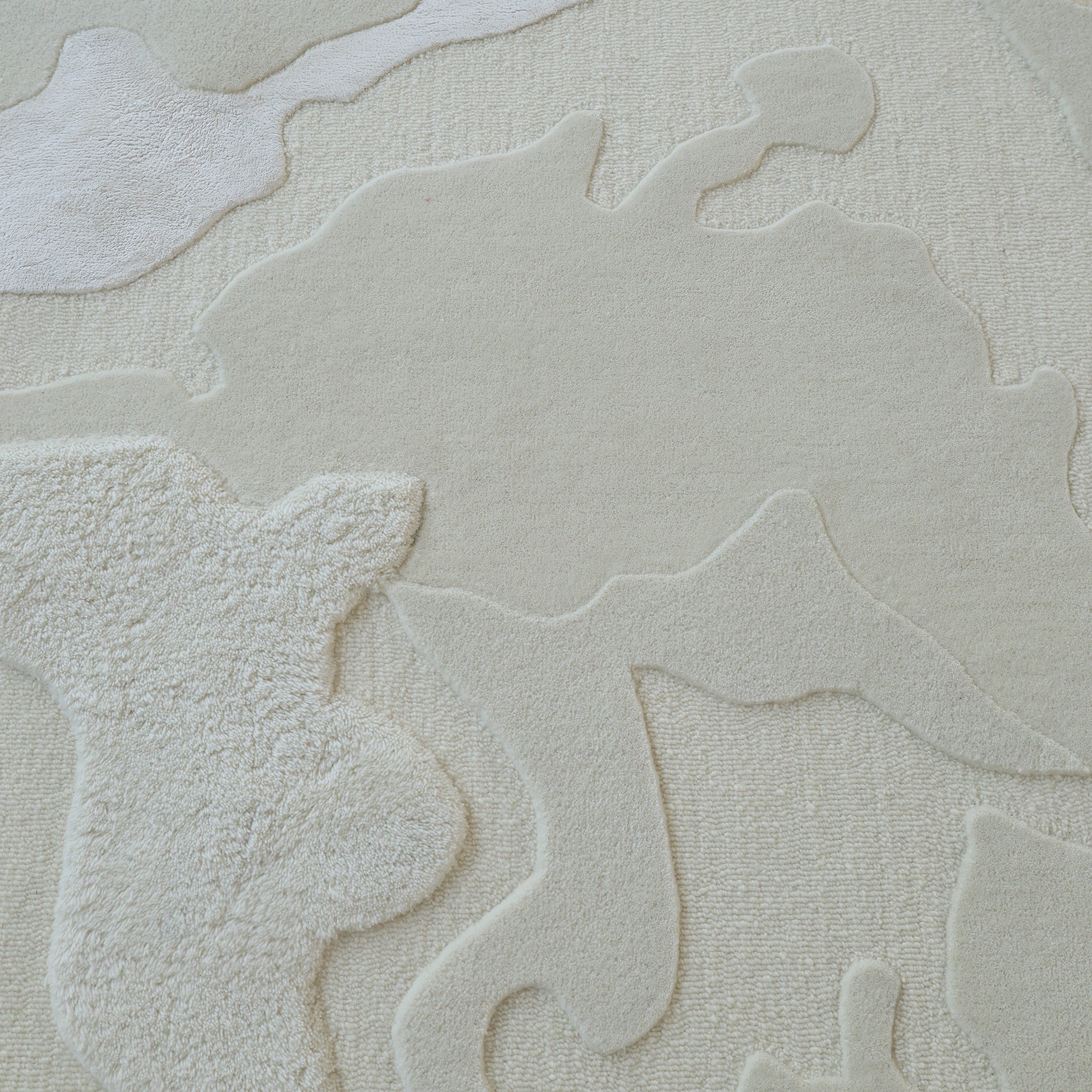 The Handcrafted Natural White Area Rug – HTWV-129 by RAMSHA HOME features an off-white, textured surface with abstract shapes and raised patterns. Varying pile heights add depth and dimension for a chic, modern look in any space.