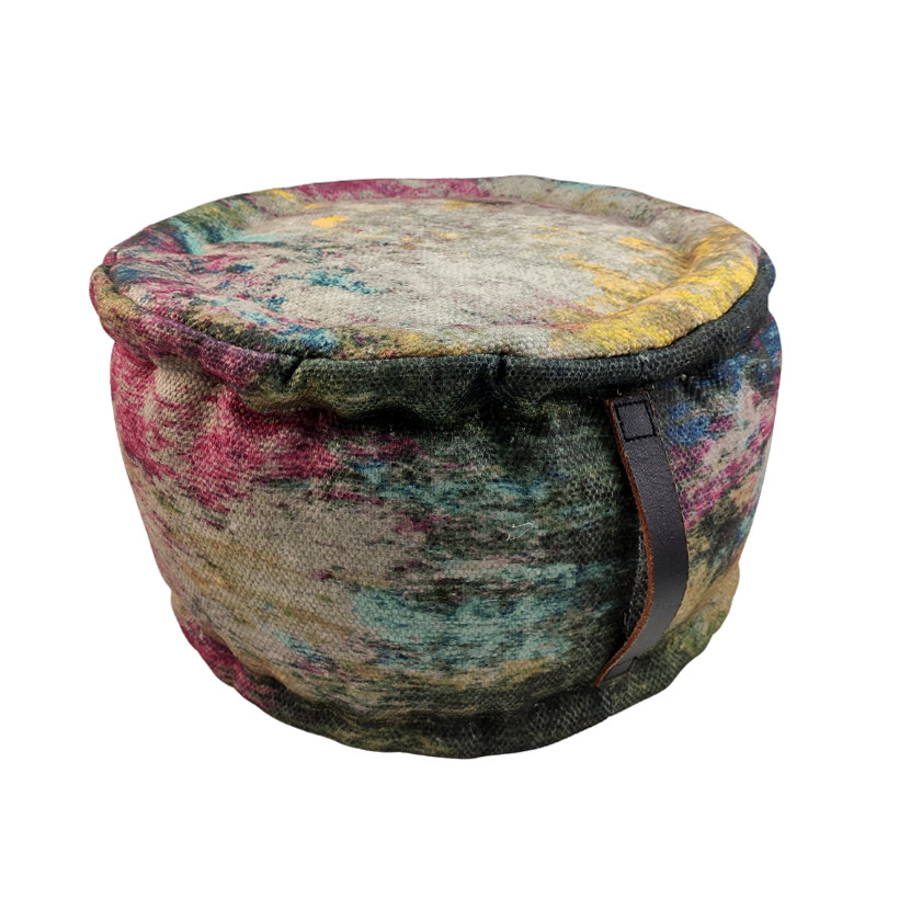 The RAMSHA HOME Printed Multi Color Pouf With Leather Handle is a round polyester pouf with a vibrant abstract pattern on a white base and a brown leather handle on the side.