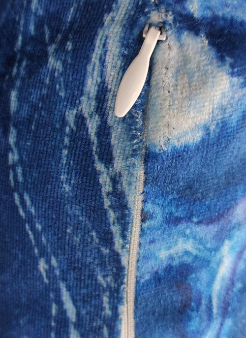 Close-up of the RAMSHA HOME Polyester Cushion Cover shows a white zipper on its durable blue and white marbled fabric with visible stitching. The cover is easy to clean and made from quality polyester.