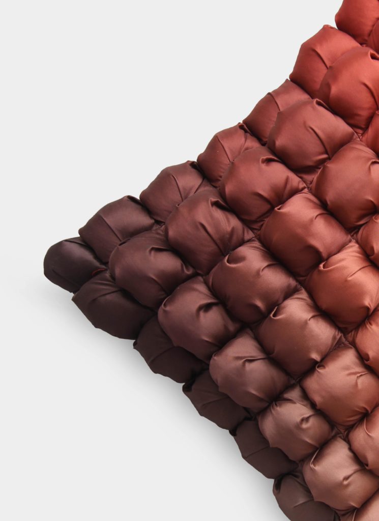 A close-up of the RAMSHA HOME Polyester Bubble Cushion Cover, showcasing textured padded tufts in brown and reddish-brown tones arranged diagonally on a white background.