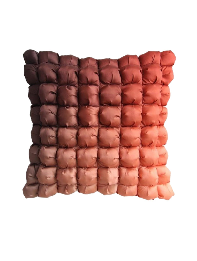 The RAMSHA HOME Polyester Bubble Cushion Cover displays a gradient of small, puffy squares shifting from dark brown in the top left to light orange in the bottom right on a white background.