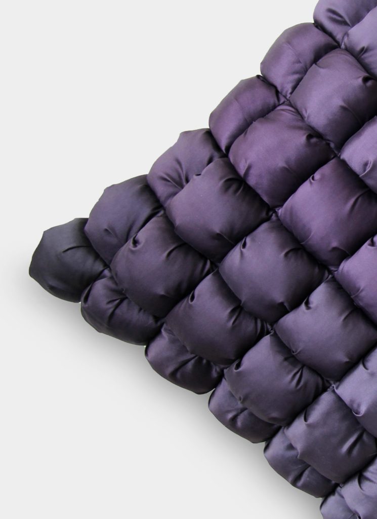 A close-up of the RAMSHA HOME Polyester Bubble Cushion Cover, showcasing a plush quilted design in shiny deep purple fabric with a gradient to darker tones arranged diagonally.