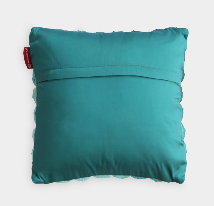 The RAMSHA HOME Polyester Bubble Cushion Cover is a square teal cover with smooth polyester fabric, a horizontal seam on the back, and a small red tag on the left side. The product is shown against a plain white background.