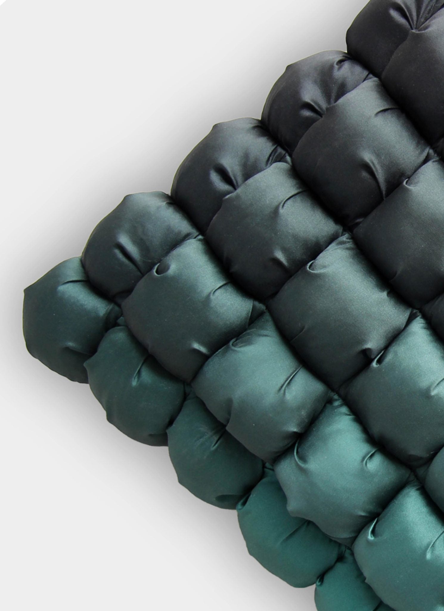 Close-up of the RAMSHA HOME Polyester Bubble Cushion Cover, featuring a quilted, pillow-like texture in green and black shades with a grid pattern, set against a light grey background.