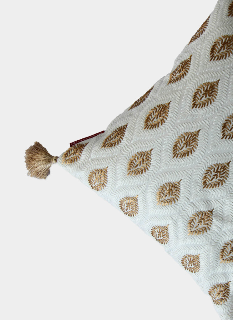 The RAMSHA HOME White & Gold Polyester Cushion Cover CS-016 features a luxe leaf pattern and tassel accent, shown in close-up against a plain white background to highlight its elegant design.