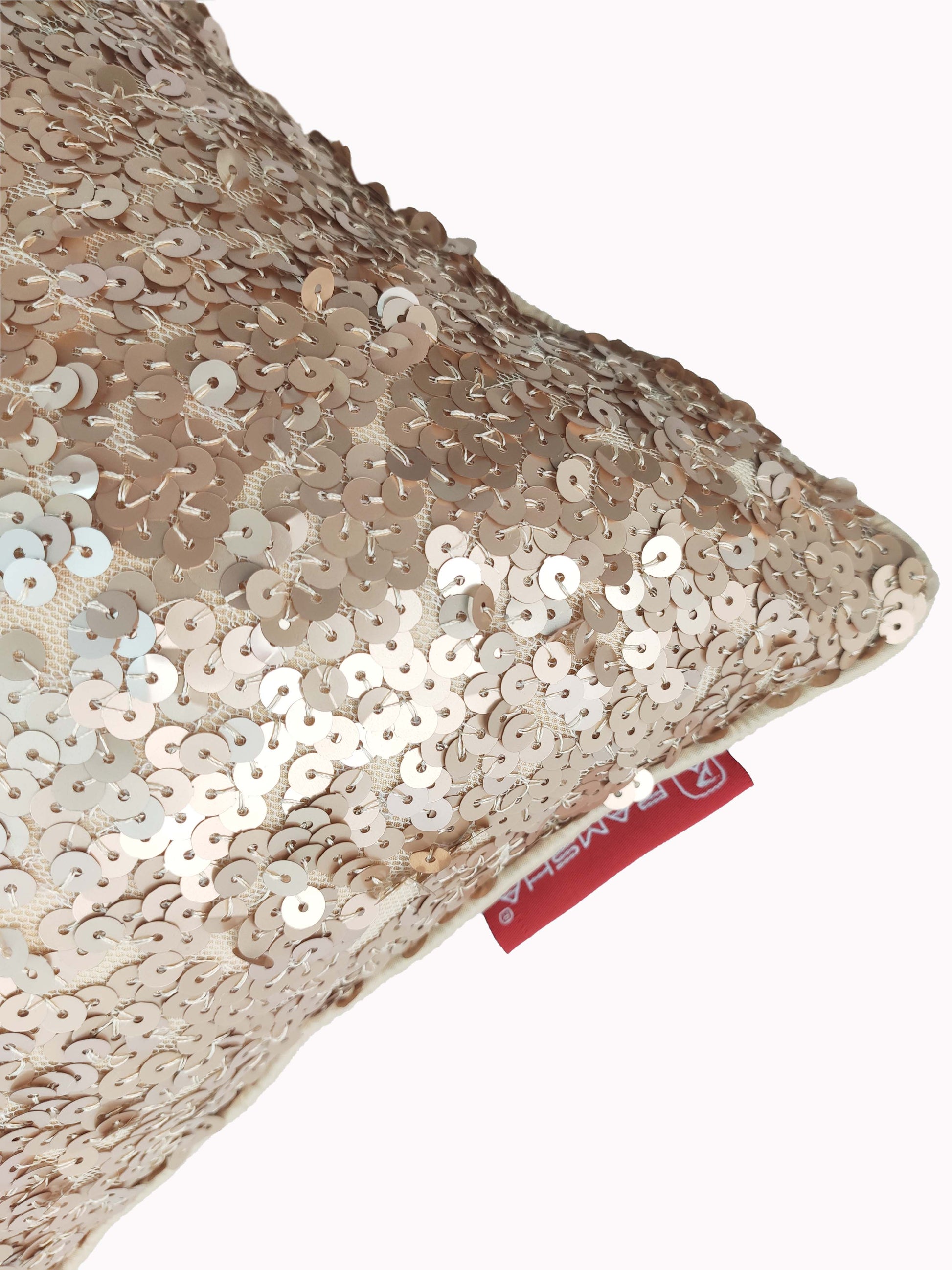 A close-up of the RAMSHA HOME Polyester Sequine Cushion Cover, featuring shiny light gold sequins and a small red tag—an elegant choice for home decor or to add sparkle to your living room.