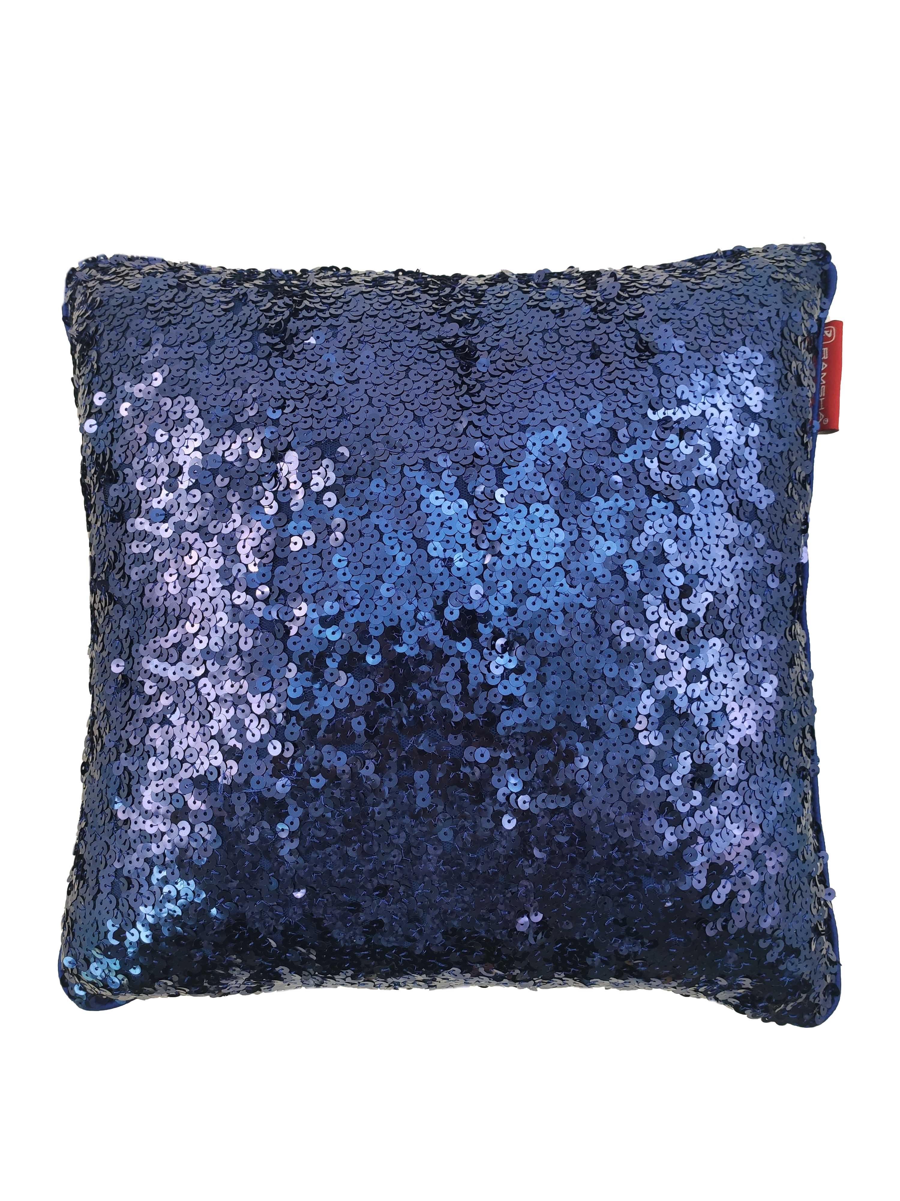 The RAMSHA HOME Polyester Sequine Cushion Cover features shiny dark blue sequins that reflect light for a shimmering look, accented by a small red tag—perfect to add sparkle and style to your living room decor.