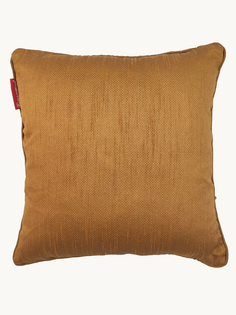 The RAMSHA HOME Polyester Sequine Cushion Cover features a square golden-brown textured design with a subtle sheen and red fabric tag on the top left edge, perfect for adding elegance to your living room. Set against an off-white background.