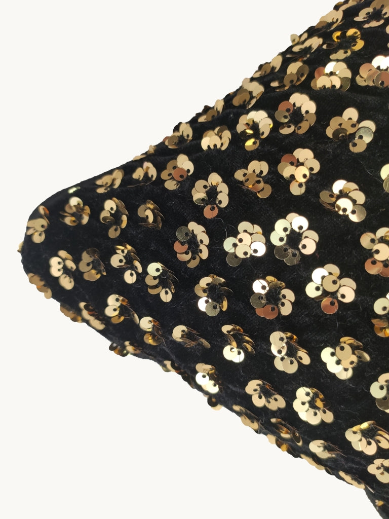 Close-up of the corner of the RAMSHA HOME Decorative Polyester Cushion Cover in black, featuring shiny gold sequins in small clusters, set against a plain white background.