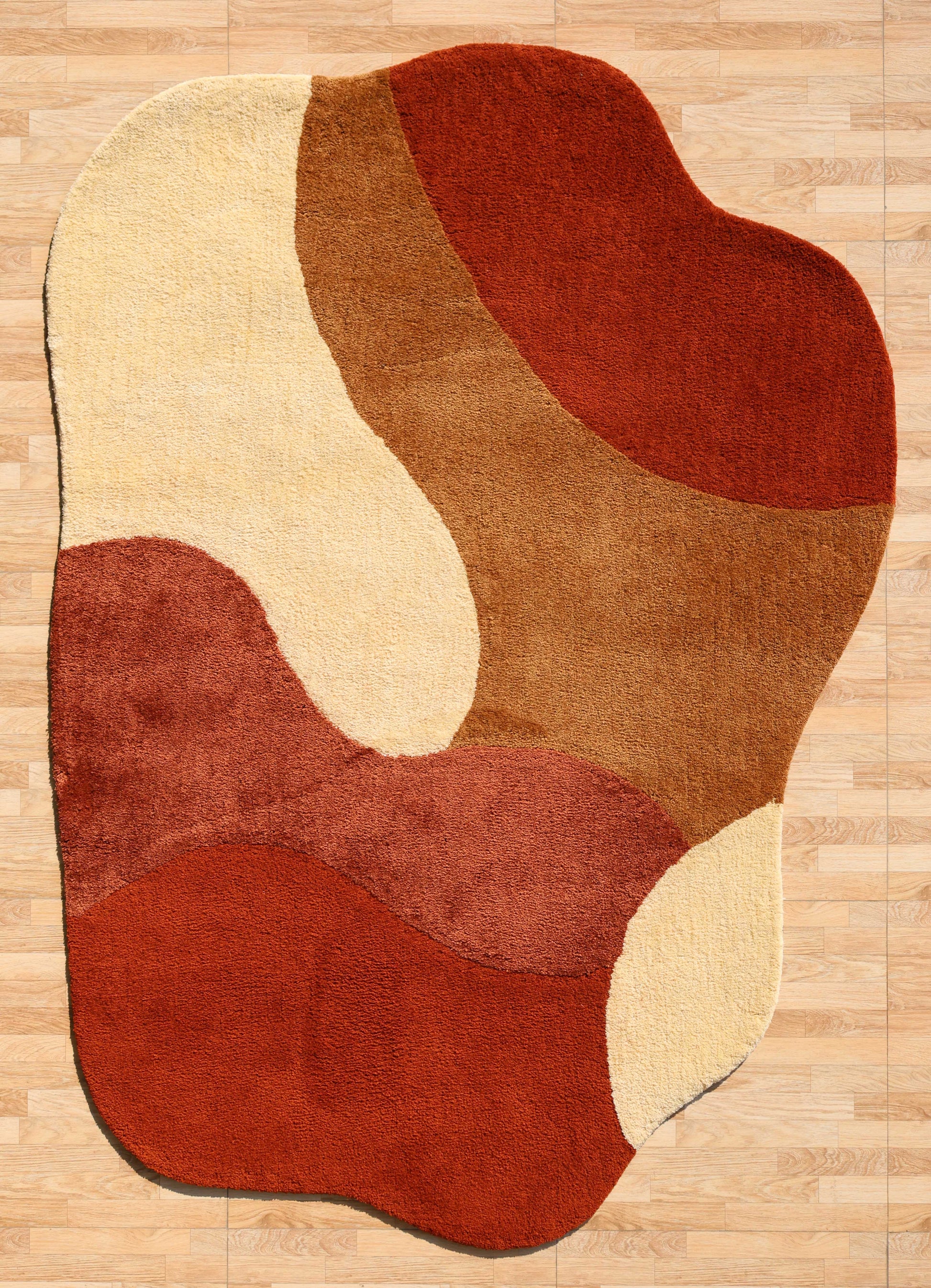 The RAMSHA HOME Terracotta Beige Soft Irregular Shape Shaggy Rug (SG 046) features plush, wavy layers in red, brown, and beige tones, adding a cozy, organic touch to light wood floors with its unique curved pattern.