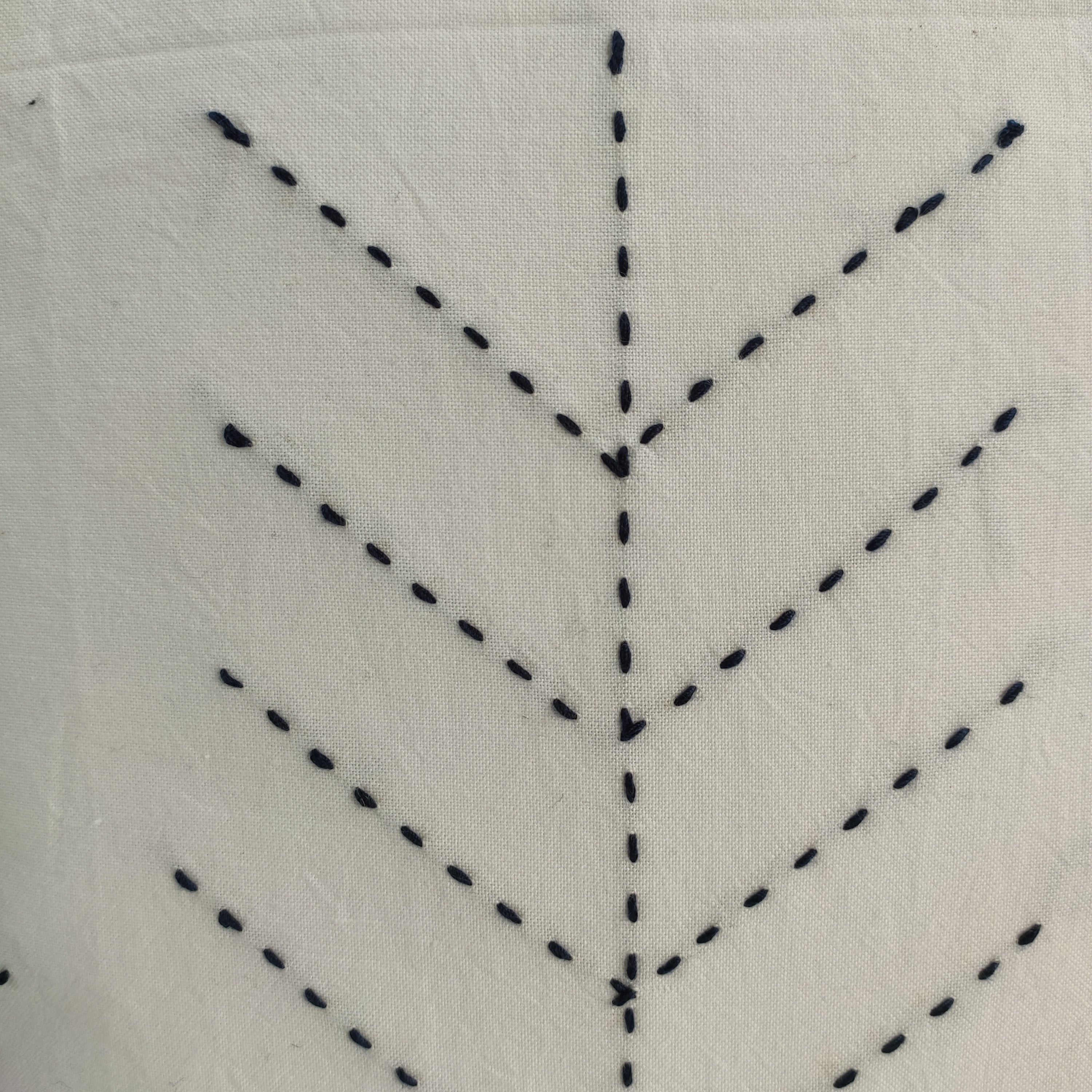 Close-up of RAMSHA HOME's Embroidery White and Black Cotton Cushion with Tassel (CS-191), featuring hand-sewn black dashed lines in a chevron pattern on white fabric.