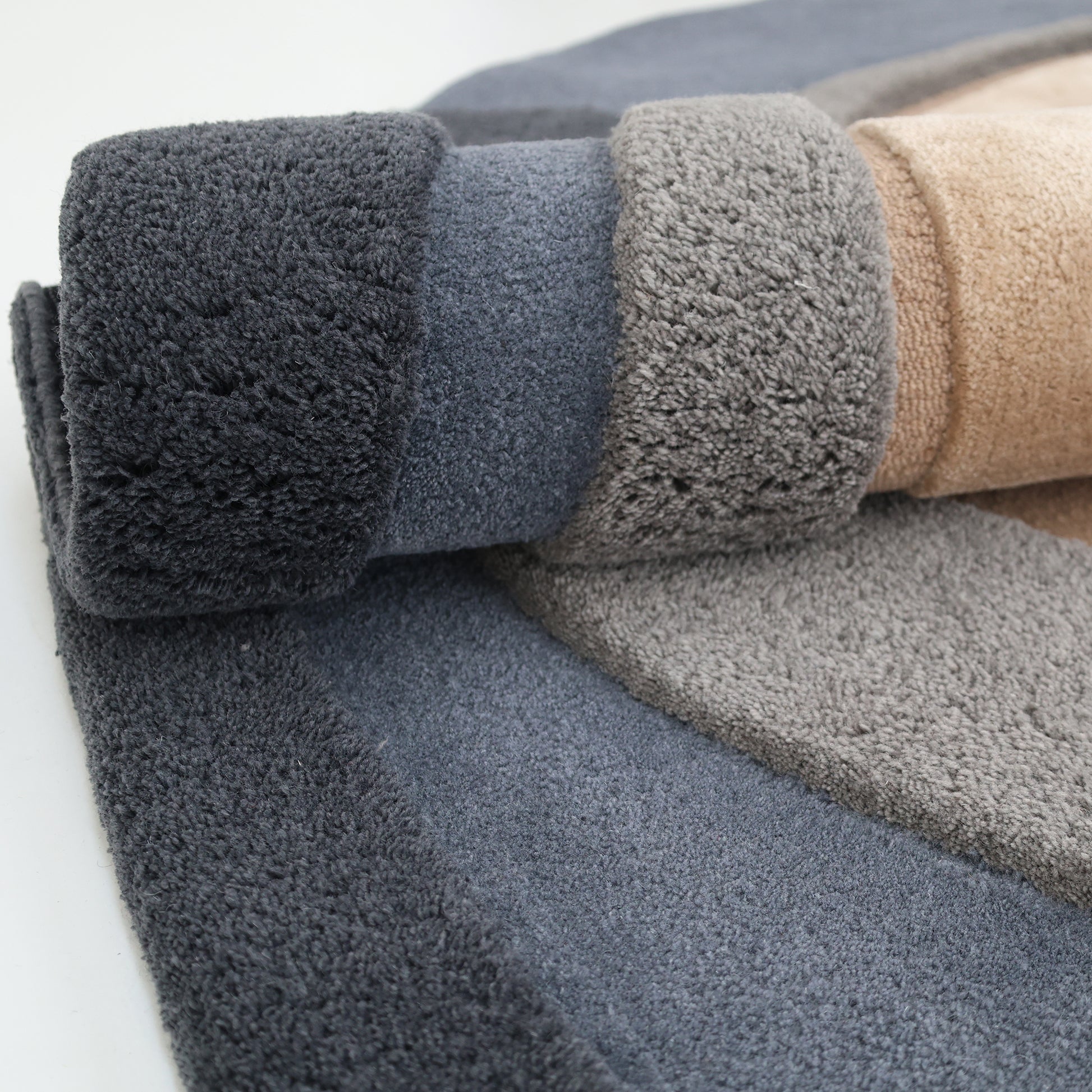Close-up of the RAMSHA HOME Oval Shape Home Decor Multi Color Rug HTWV-90, featuring plush hand-tufted sections in dark gray, light gray, and beige with rolled edges for a stylish modern layered look.