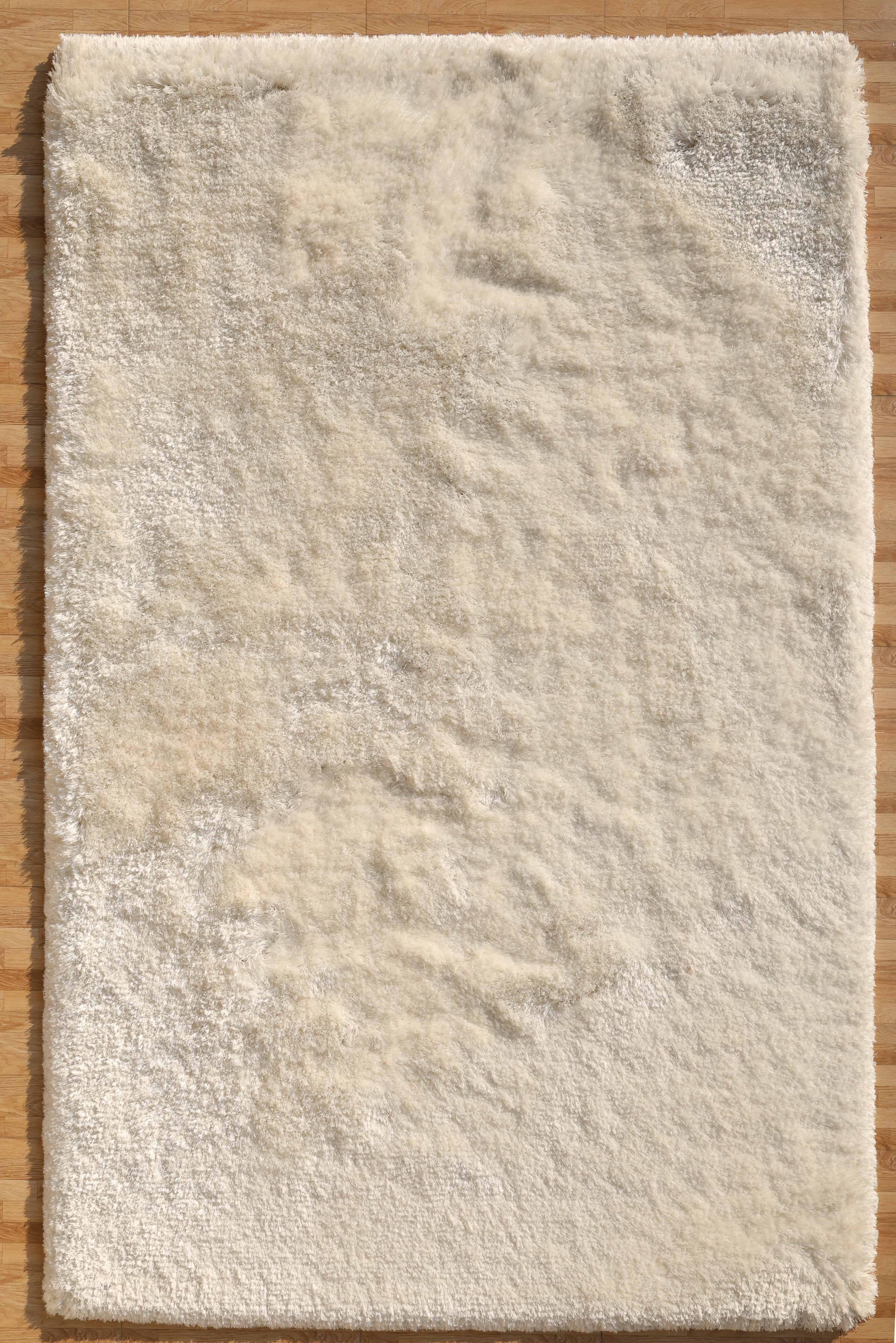 The RAMSHA HOME White Color Plush Shaggy Area Rug - SG 040 features soft, fluffy fibers and a rectangular shape, adding cozy texture and subtle shadows to any wooden floor.
