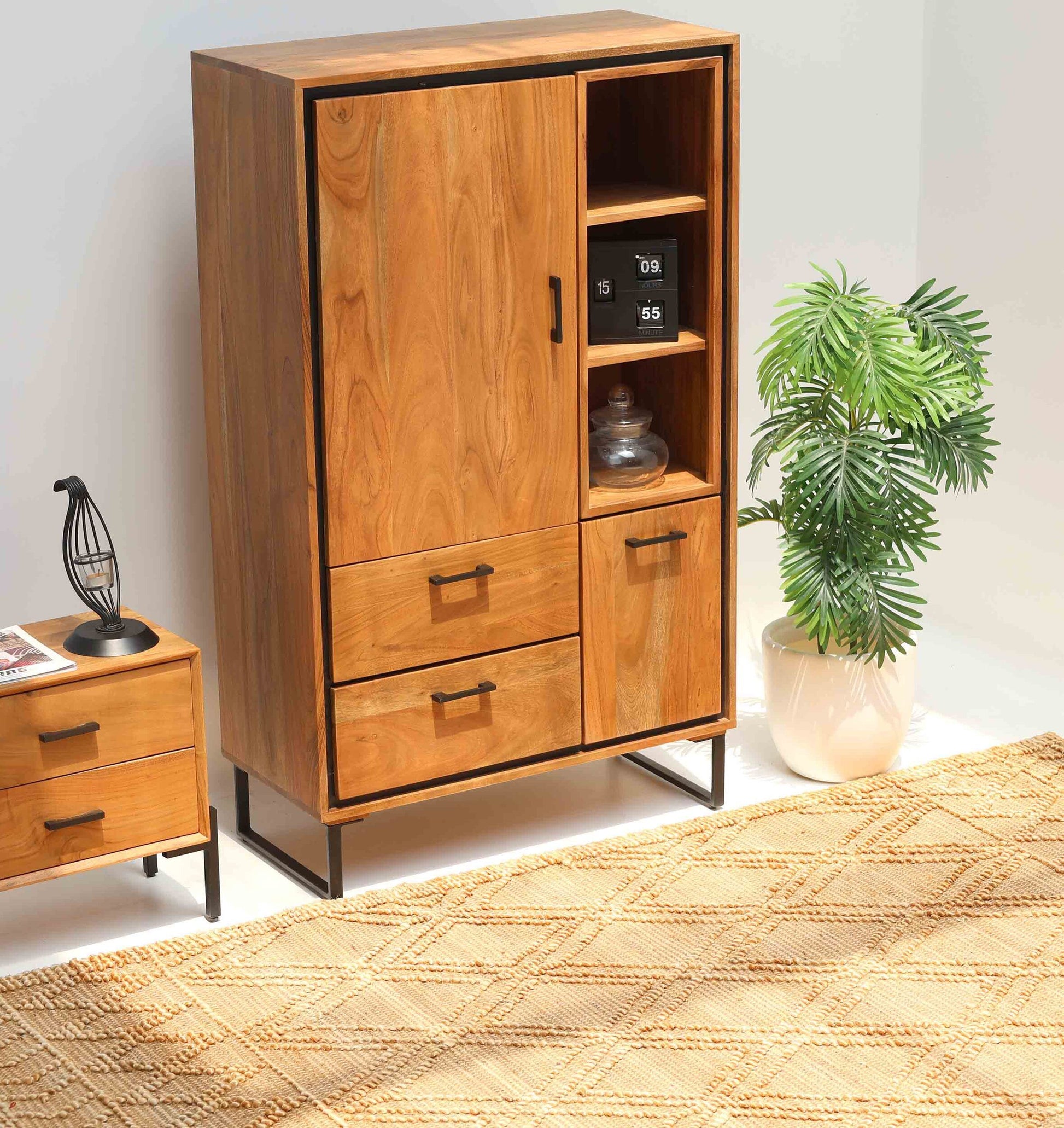 The Handcrafted Acacia Wood Cabinet Almirah with open shelves by RAMSHA HOME, featuring black metal legs, stands beside a matching nightstand, a potted plant, and a beige patterned rug in this bright living room.