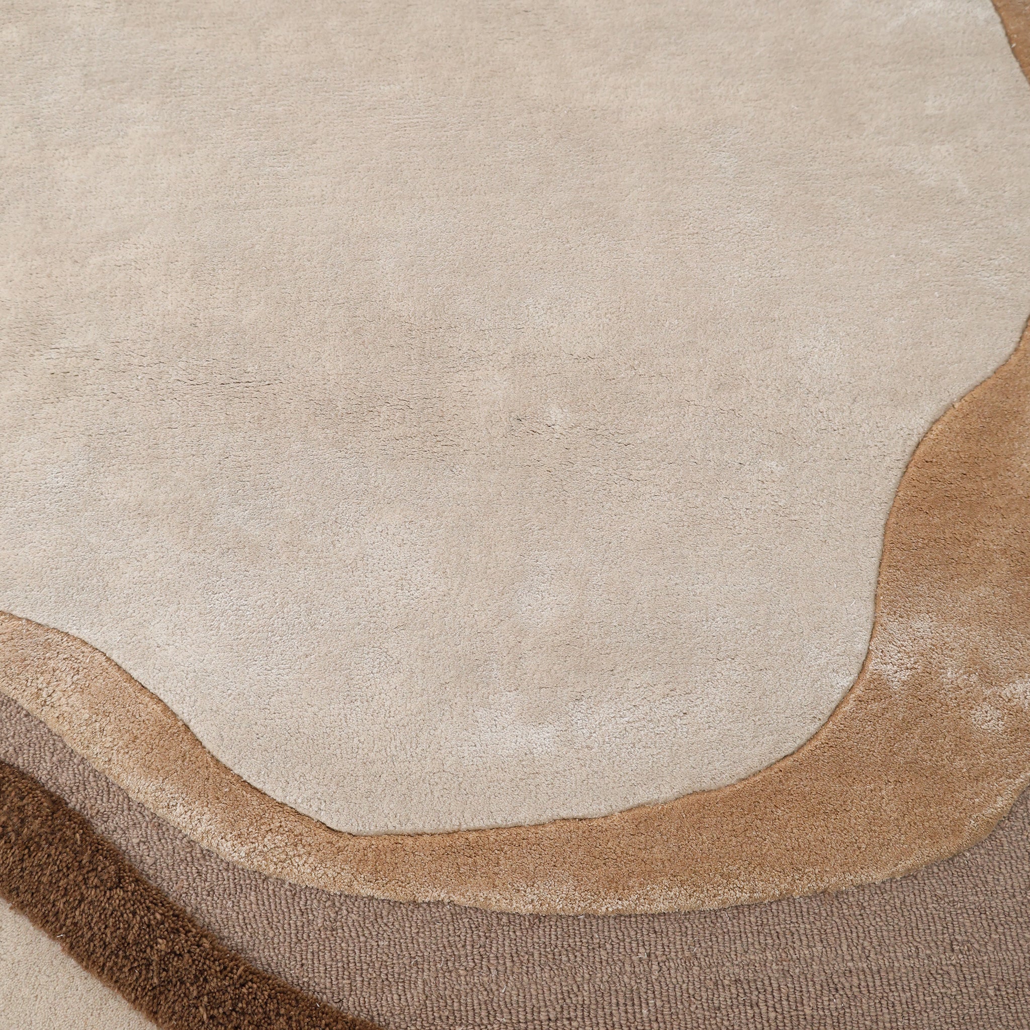 A close-up of the RAMSHA HOME Vibrant Round Shape Handmade Rug - HTWV 95 (200 cm), a hand-tufted wool area rug with abstract, wavy beige, tan, and brown patterns and organic contours for a modern neutral look.