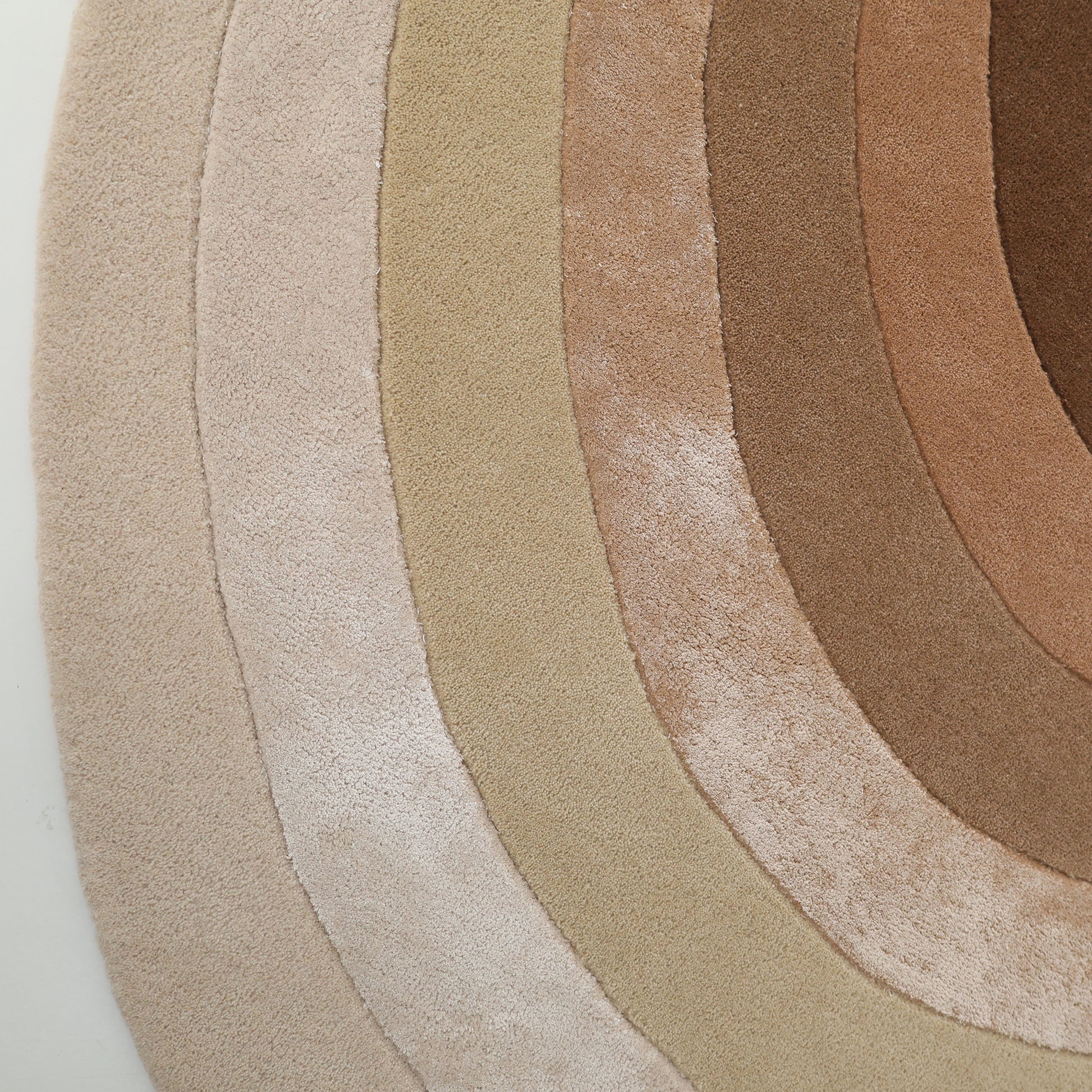 A close-up of the RAMSHA HOME Vibrant Living Room Handmade Rug - HTWV-81 B (200x300cm), a hand tufted wool piece with concentric arcs in beige, tan, and brown tones, creating a stunning gradient from light to dark.