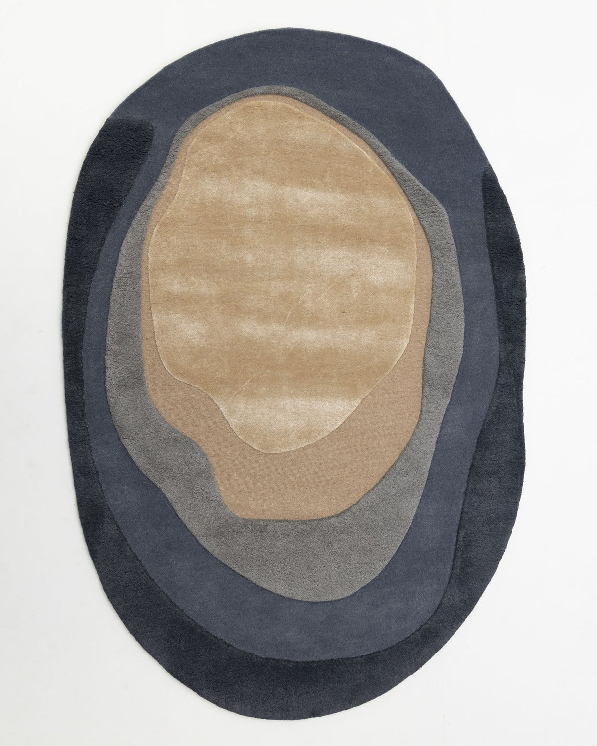 Introducing the Oval Shape Home Decor Multi Color Rug HTWV-90 by RAMSHA HOME—a modern wool rug, hand tufted for exceptional comfort. Featuring layered, irregular concentric shapes in shades of beige, taupe, and dark gray on a white background, this oval rug evokes the look of a topographic map and brings contemporary style to your space.