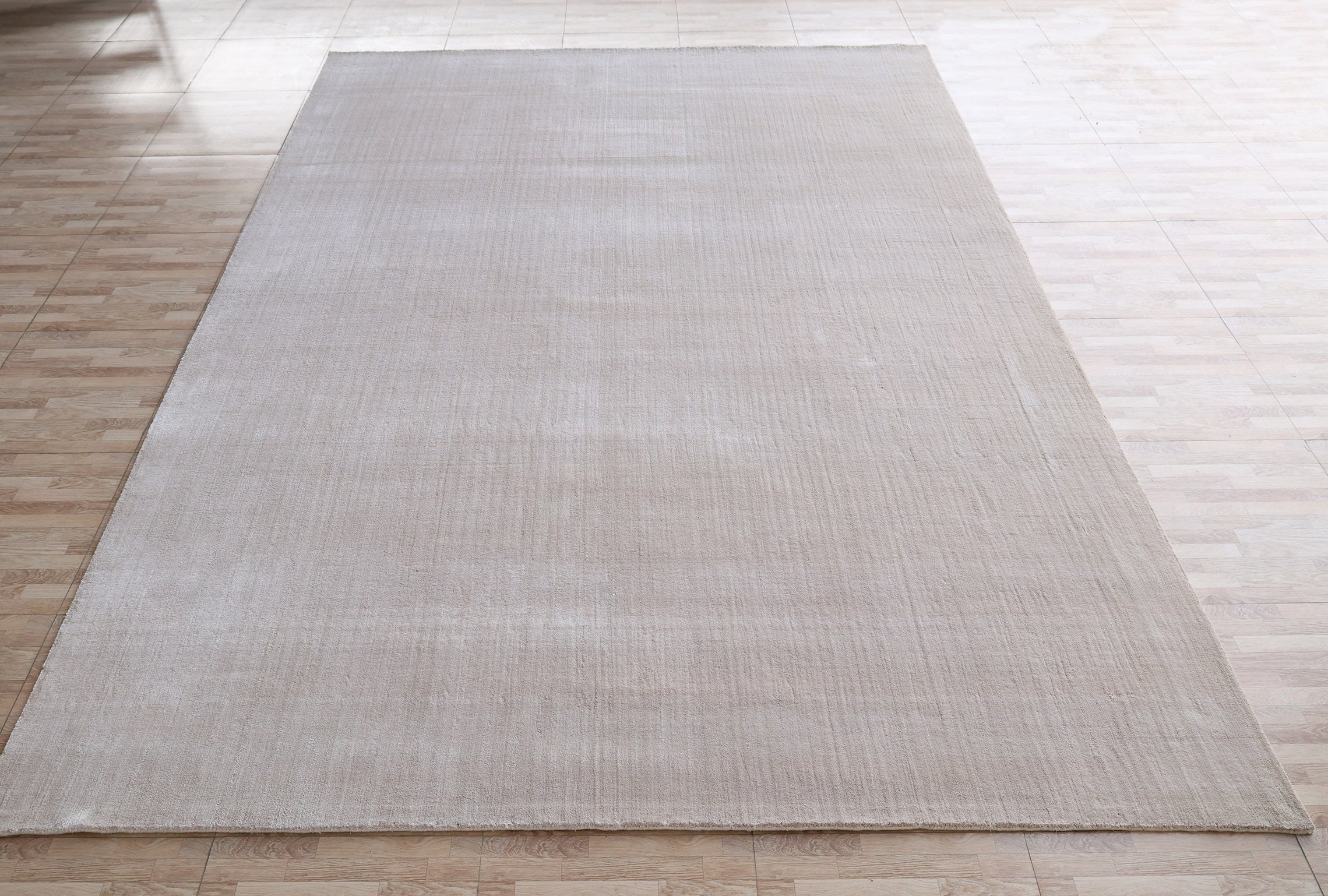 The RAMSHA HOME Handmade Plain Beige Area Color Rug (LKH-047), sized 300x400 cm, is laid on a light wood-patterned floor in a bright, empty room. The rug is solid beige with minimal texture and no visible patterns or designs.