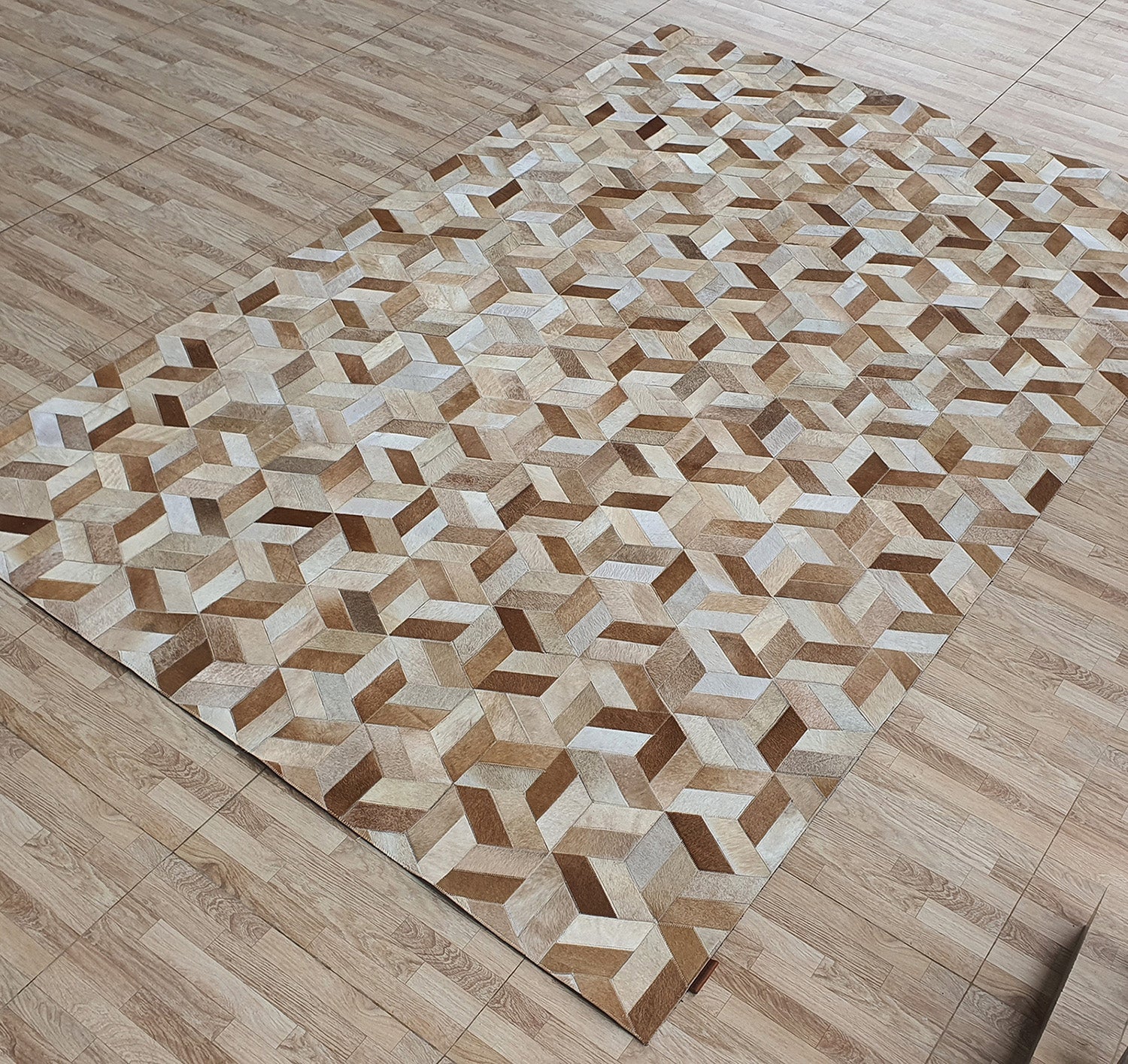 The RAMSHA HOME Geometric Cube Pattern Handmade Leather Area Rug LR-012 features a 3D optical illusion in shades of brown and beige, displayed on a light wood-patterned floor.