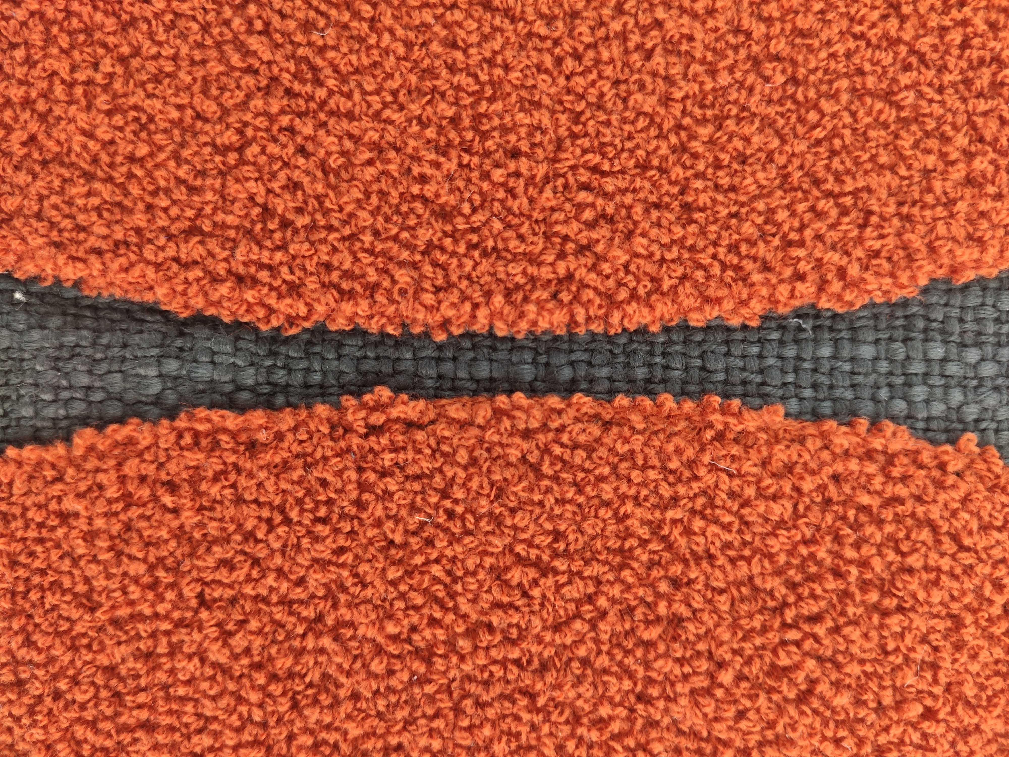 Close-up of an orange textured carpet with a black seam running horizontally—an eye-catching detail ideal for stylish home décor or pairing with the RAMSHA HOME Rust Color Cushion CS-121.