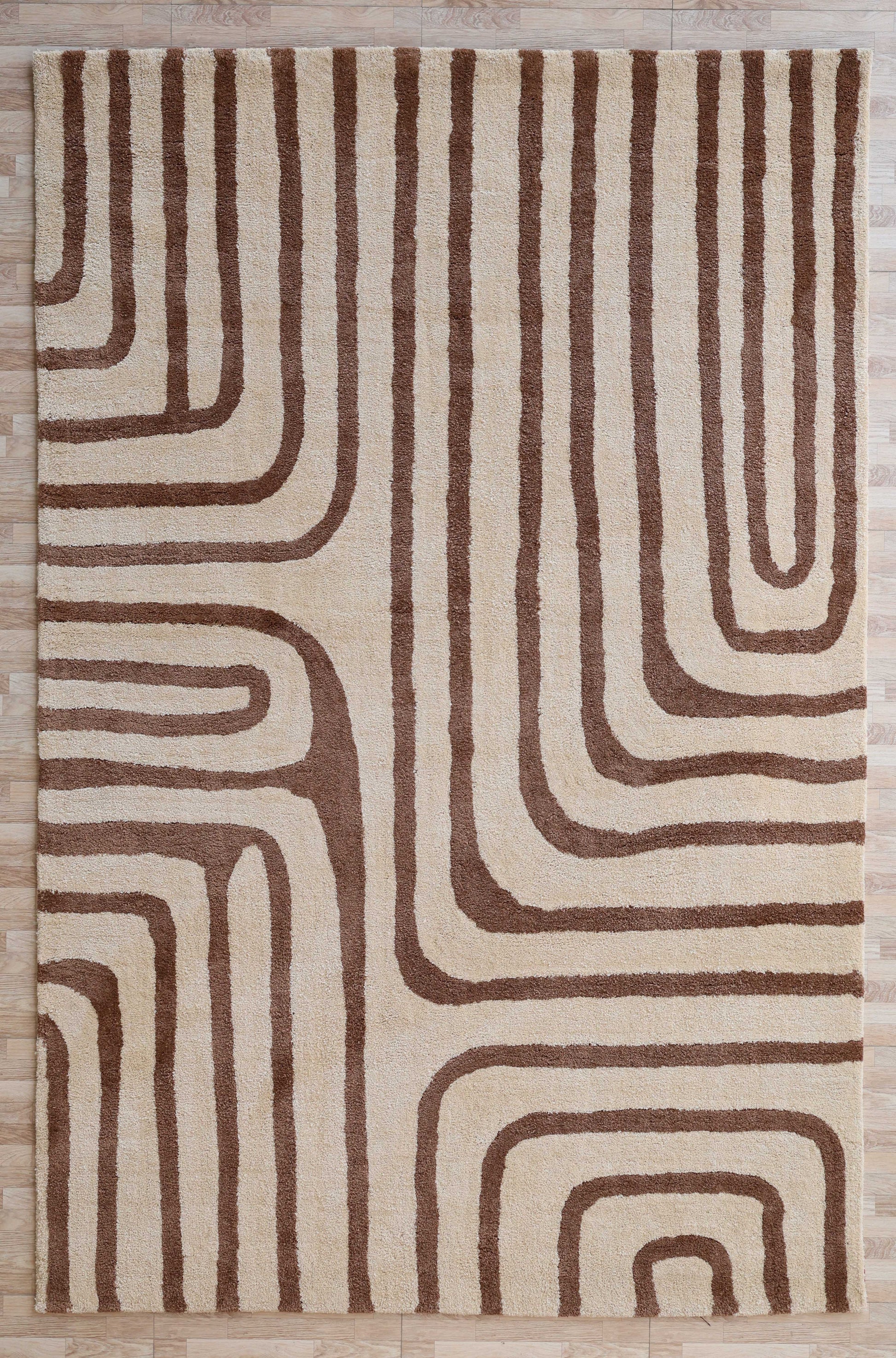 The RAMSHA HOME Beige and Brown Shaggy Area Rug for Large Living Room (SG 050) features plush pile with abstract retro brown lines on a beige background, displayed here on a light wooden floor.