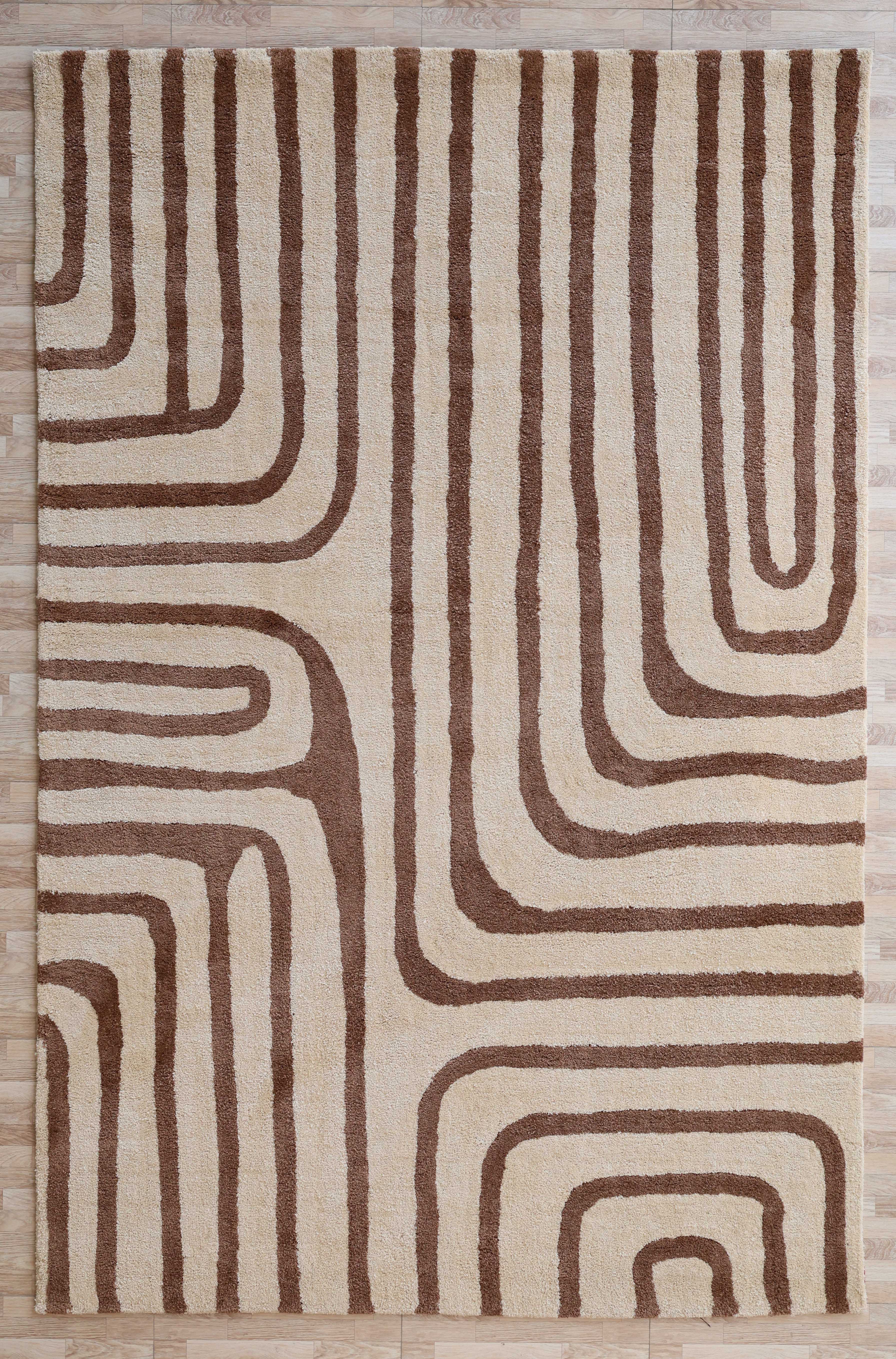 The RAMSHA HOME Beige and Brown Shaggy Area Rug for Large Living Room (SG 050) features plush pile with abstract retro brown lines on a beige background, displayed here on a light wooden floor.