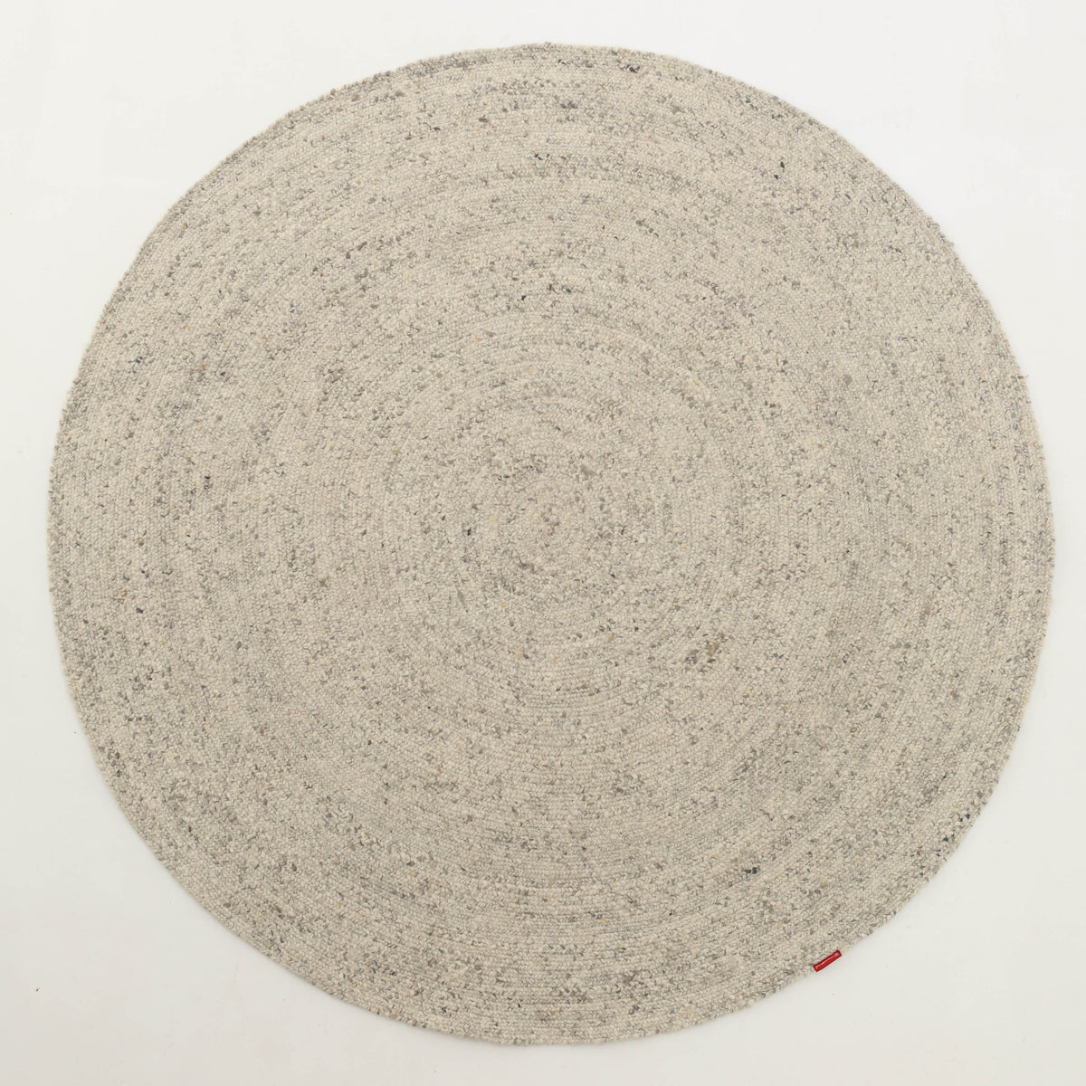 A handmade, round beige braided wool area rug by RAMSHA HOME (model BR 100) featuring a subtle spiral pattern is displayed on a white background, with a small red tag attached to the edge.