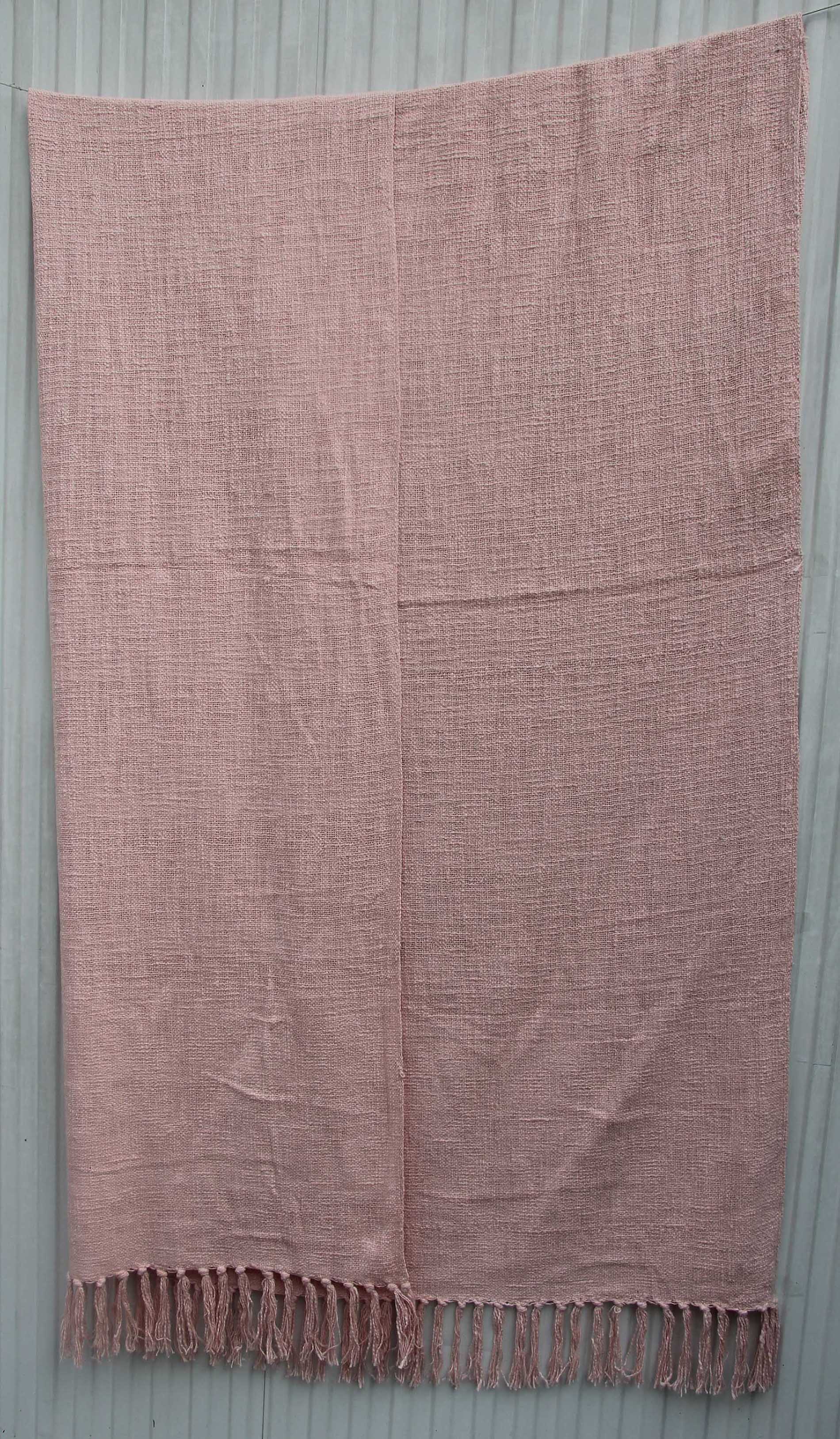 The Pink Color Cotton Throw for Sofa TAL 042 (125x150 cm) from Ramsha Home features a light pink hue, subtle woven texture, and twisted fringe tassels—perfect for adding breathable comfort and style to any space.