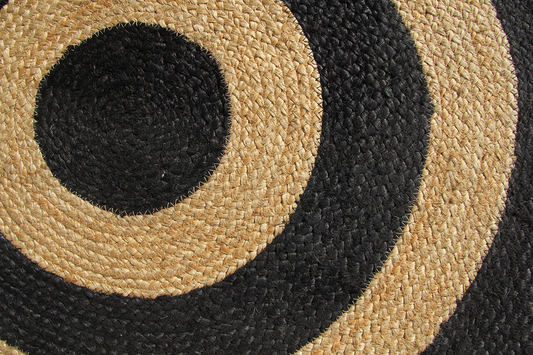 Close-up of the RAMSHA HOME Handmade Natural & Black Jute Floor Braided Rug (BR 072), featuring concentric circles in beige and black for a bold, textured pattern.