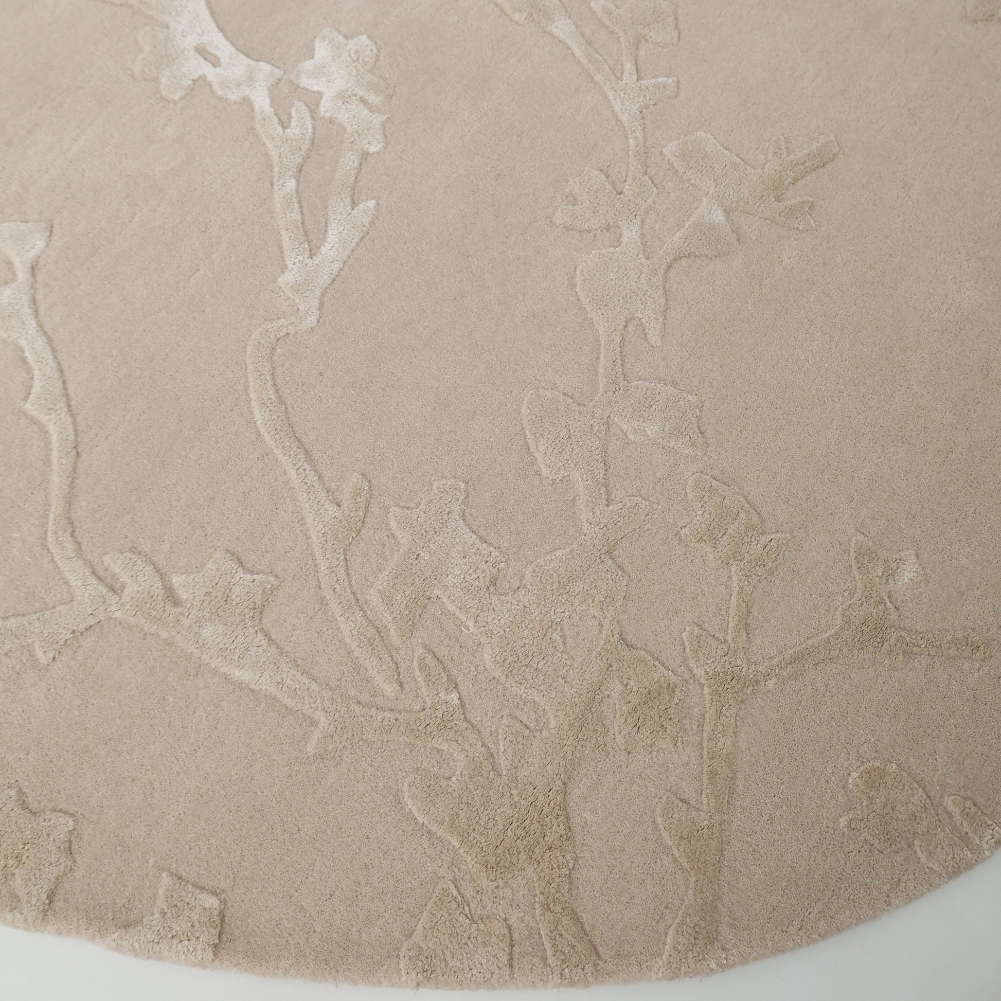 The RAMSHA HOME Decorative Handmade Area Rug HTWV-118 features a round beige design with a raised floral vine texture, offering an elegant and neutral touch—perfect as a bedroom rug.
