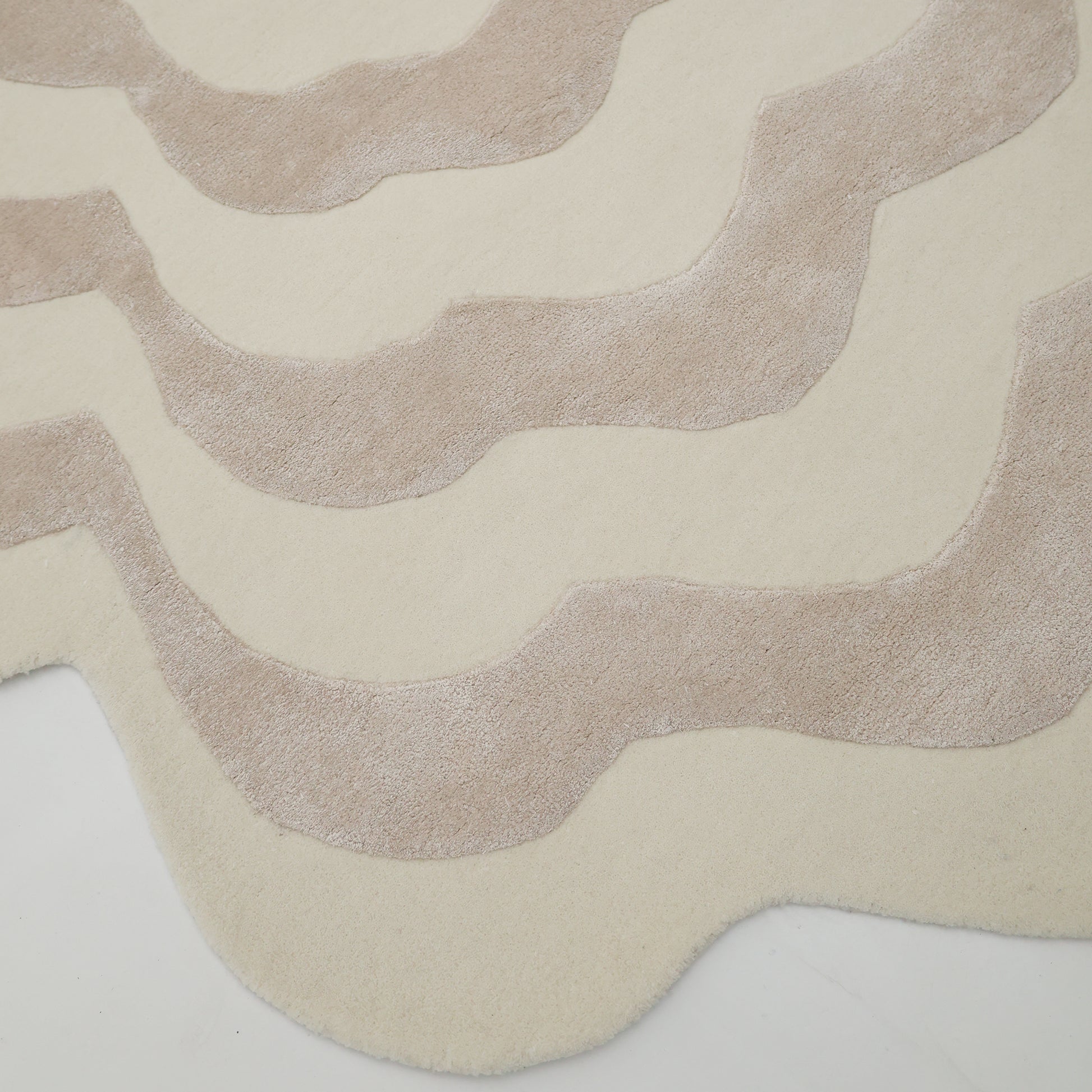 The RAMSHA HOME Beige & Cream Wavy Handmade Area Rug (HTWV-144) features an abstract design with wavy, irregular lines and scalloped edges, creating a unique organic pattern in neutral tones.