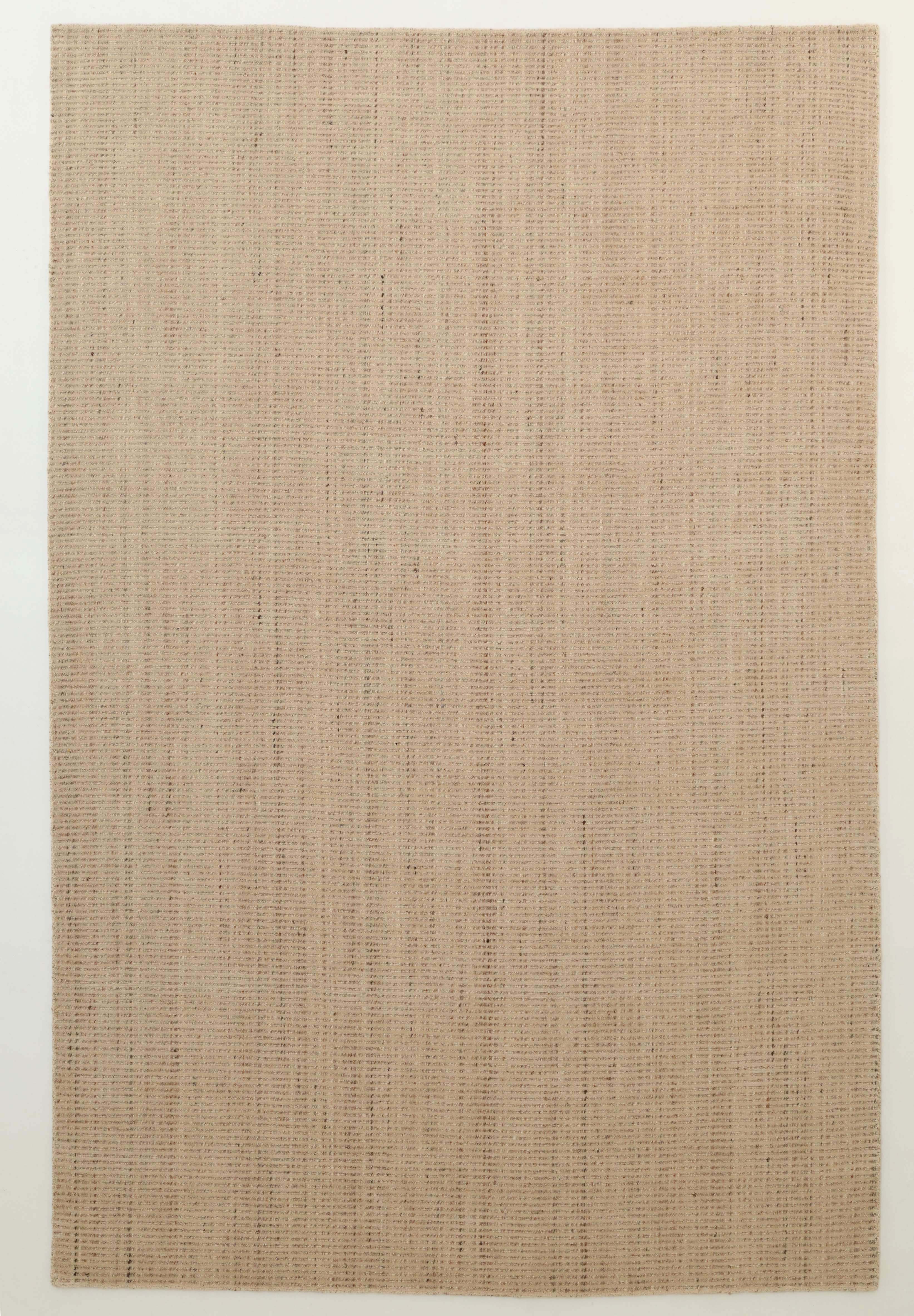 The Handmade Natural Wool Rug – Textured Beige Area Rug (HLR-002) by RAMSHA HOME features a minimalist rectangular design in beige, handwoven with natural fibers, and is shown on a plain light-colored floor.