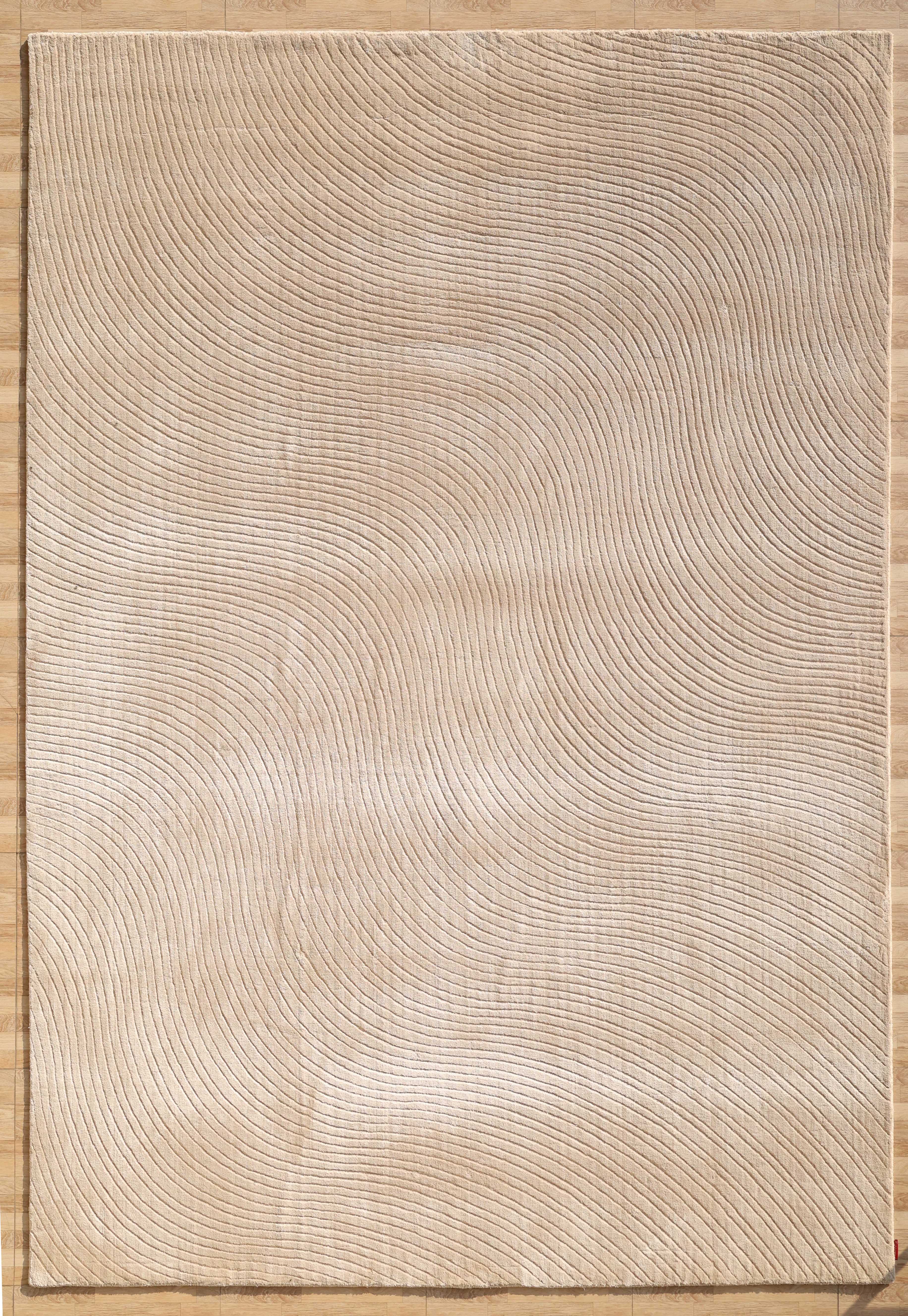 The RAMSHA HOME Handmade beige Wave Modern Abstract High-Low Area Rug (250x350 cm, LKH-049) features thin wavy concentric lines and a subtle embossed texture, creating a ripple effect that complements wooden floors.