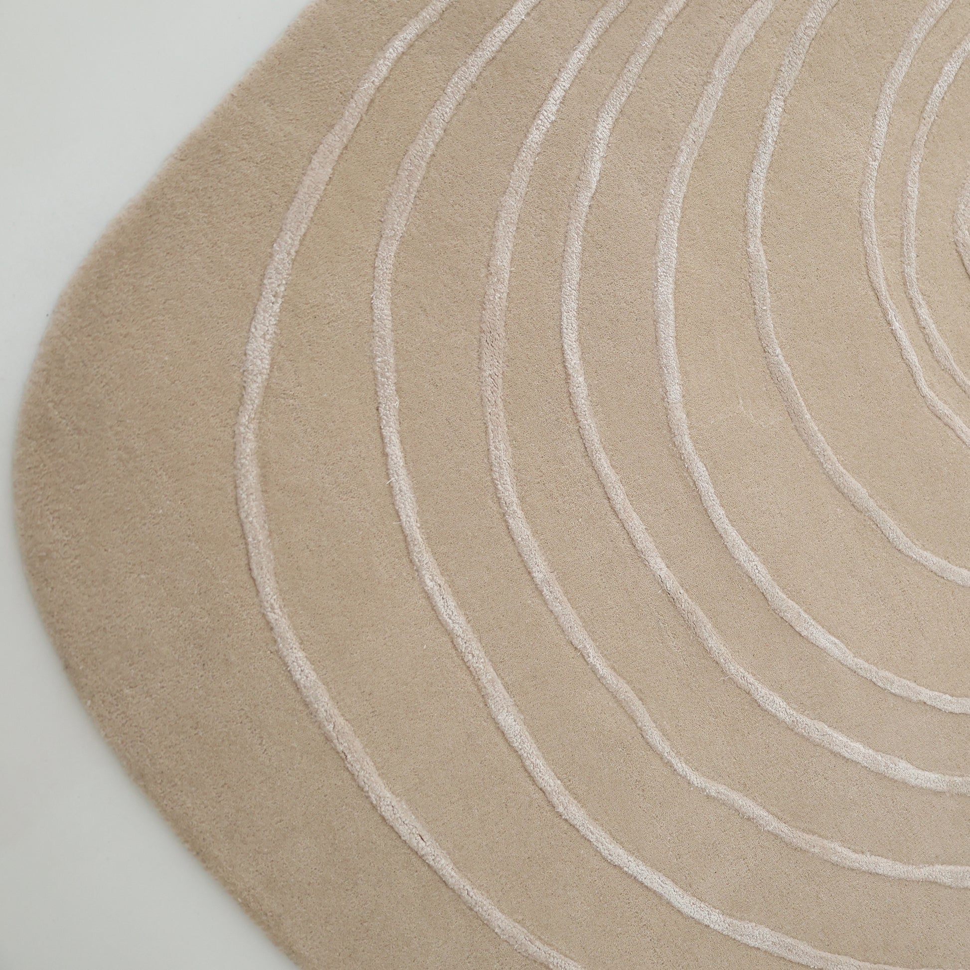 The RAMSHA HOME Luxurious Off-White Wool & Tencel Handmade Area Rug (HTWV 110, 200x300cm) features an irregular, rounded edge and raised curved lines in concentric patterns for a textured, modern look on light floors.
