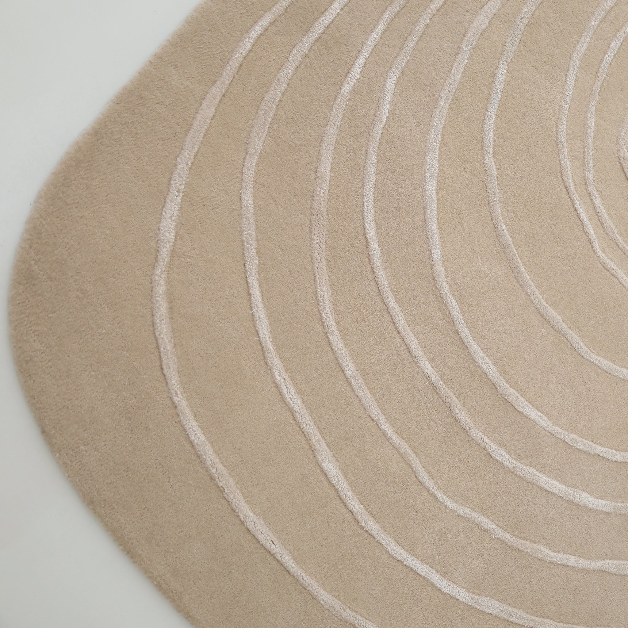 The RAMSHA HOME Luxurious Off-White Wool & Tencel Handmade Area Rug (HTWV 110, 200x300cm) features an irregular, rounded edge and raised curved lines in concentric patterns for a textured, modern look on light floors.
